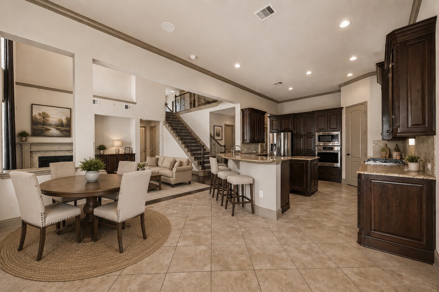 The open concept layout showcases the kitchen, breakfast area, and living room in one seamless flow. The kitchen features rich wood cabinetry, granite countertops, a stone backsplash, stainless steel appliances including a built in oven and microwave, and a gas cooktop. The island with a breakfast bar provides additional prep space and seating. A view of the staircase and second floor loft adds architectural depth. Please note, this photo has been virtually staged.