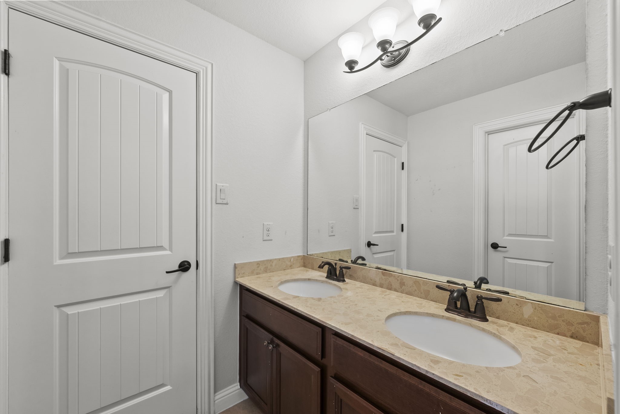 Convenient Jack-and-Jill bathroom features a dual-sink vanity with elegant counters, practical style for busy mornings!