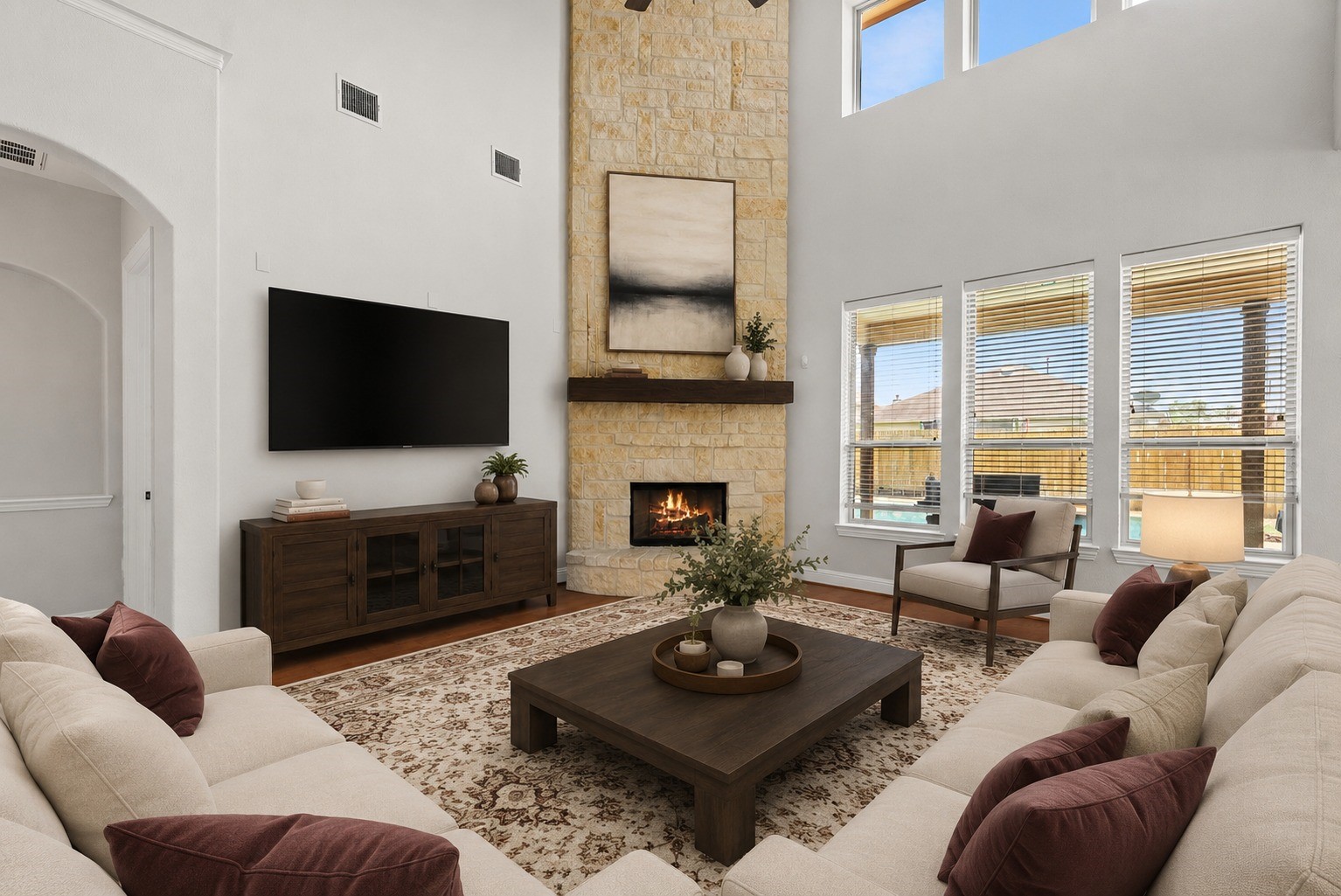 Virtually Stagged - Light filled living room stuns with soaring ceilings, a striking floor-to-ceiling stone fireplace, and windows framing serene backyard pool views!