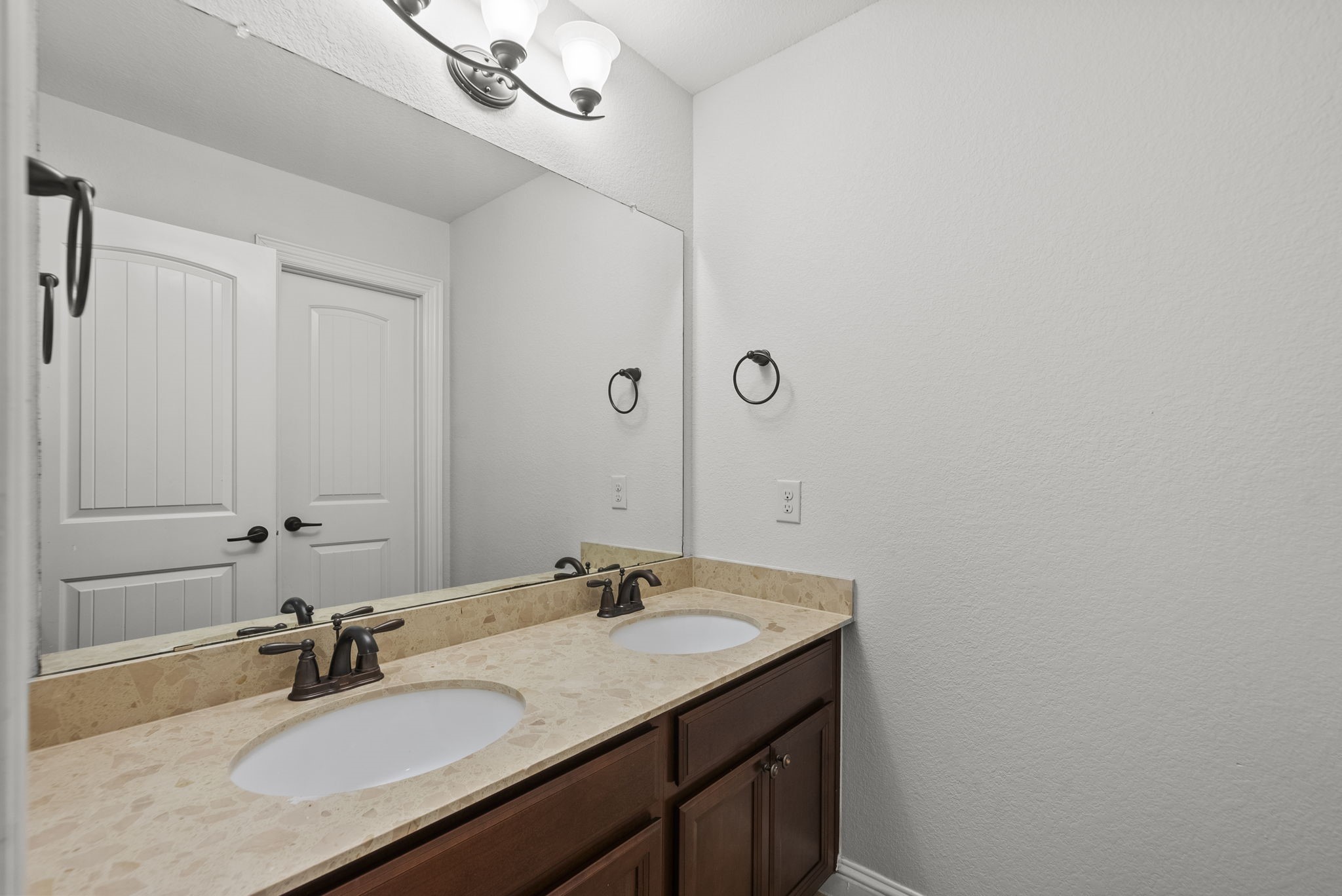 Convenient Jack-and-Jill style bath features double vanity sinks and rich counters, ideally designed for busy mornings!