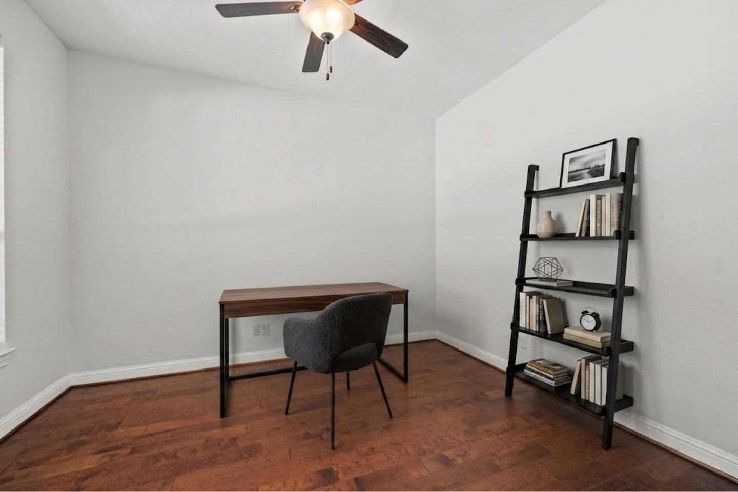 Virtually Stagged - Spacious study room featuring rich hardwood floors and a ceiling fan.