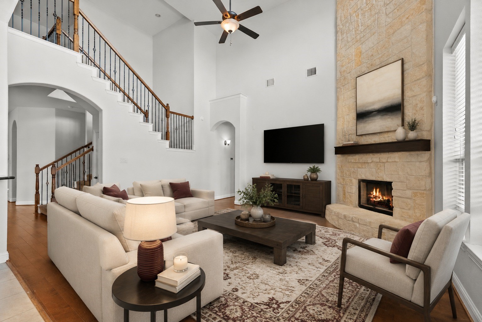 Virtually Stagged - Soaring two-story living room dazzles with a dramatic floor-to-ceiling stone fireplace, elegant wrought-iron staircase, and rich hardwood floors throughout!
