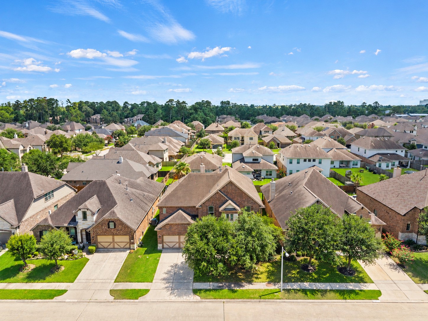 Stunning aerial view showcases this beautiful brick home nestled in a desirable, tree-lined community with lush greenery as far as the eye can see!