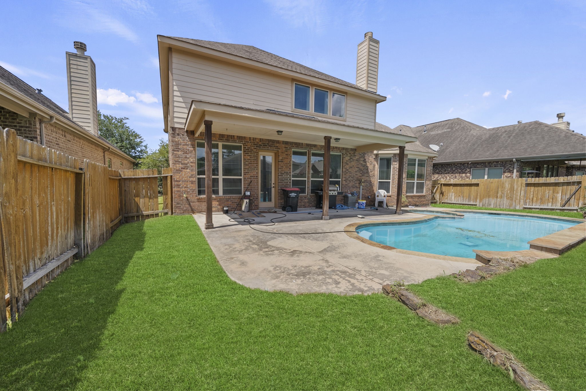 Private, fully fenced backyard retreat features a sparkling pool, spacious covered patio, and lush green lawn, outdoor living at its finest!