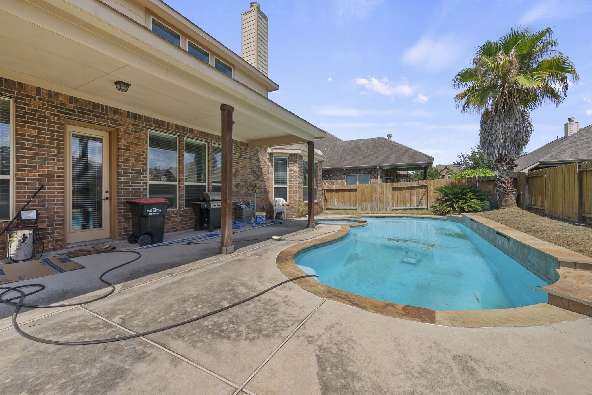 Resort-style pool and spa combo, framed by a swaying palm and expansive covered patio, sets the scene for endless summer fun!