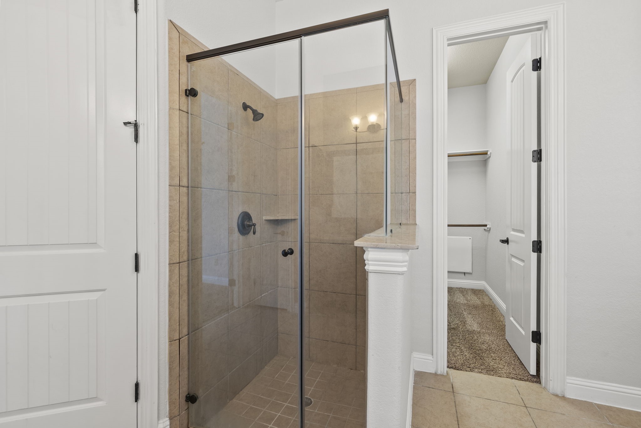 Beautifully tiled walk-in shower with a sleek frameless glass enclosure adds a spa-like touch to this well-appointed ensuite bath!