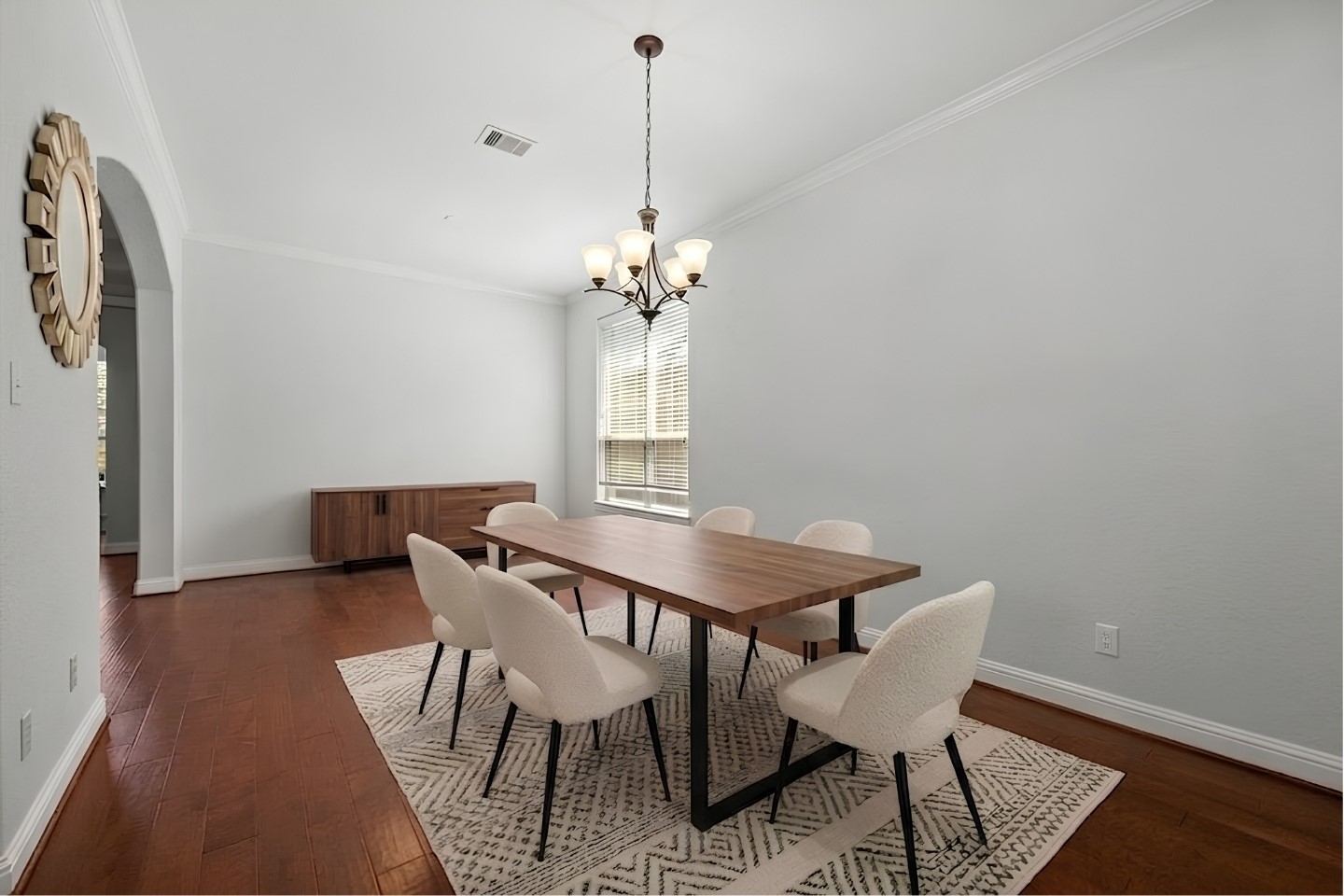 Virtually Stagged - Elegant formal dining room boasts gleaming hardwood floors, an elegant chandelier, and crisp crown molding, ready to host memorable gatherings!