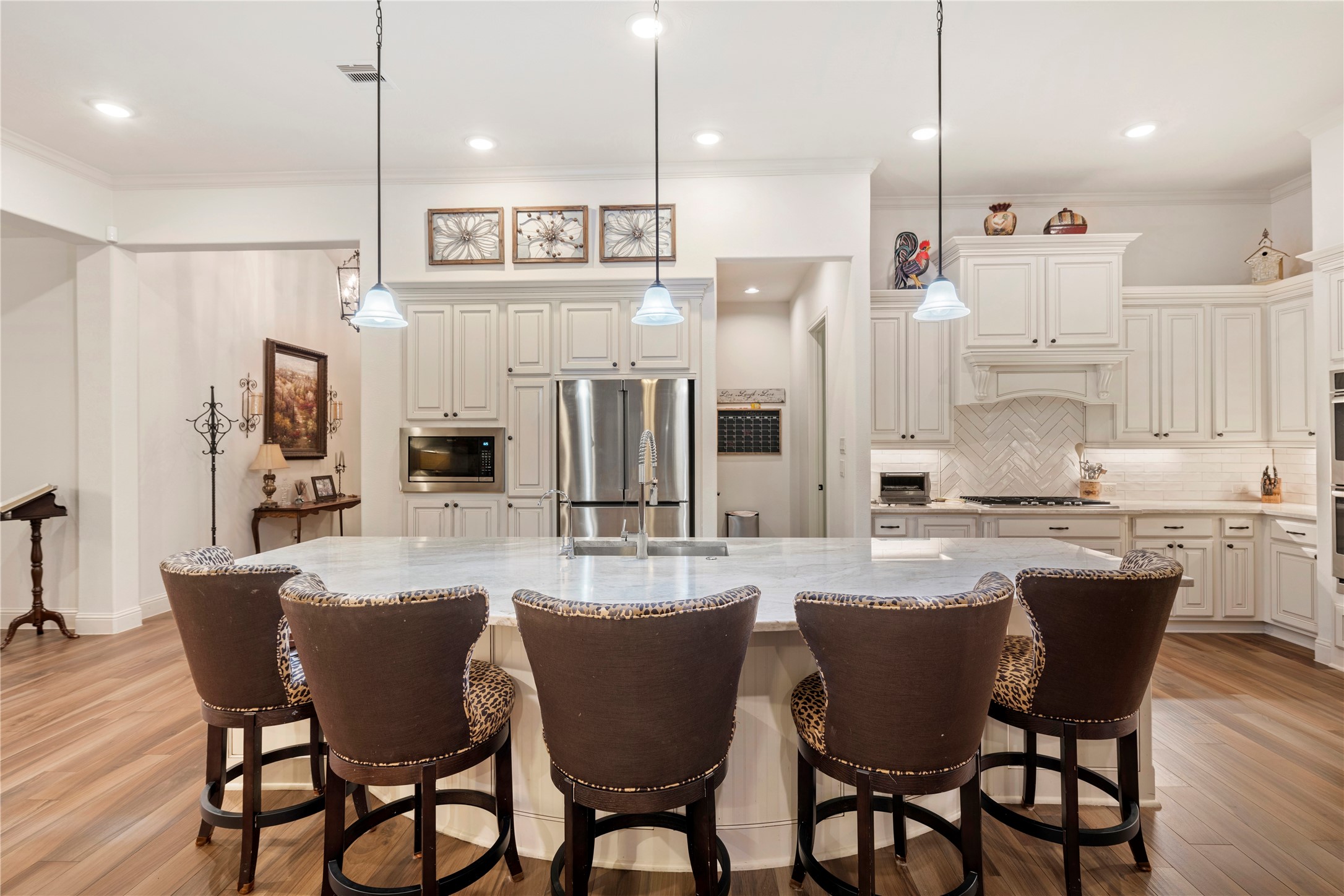 Experience the ultimate in culinary elegance with this expansive kitchen, featuring quartz countertops, an inviting island, abundant cabinet space, sleek stainless steel appliances, and an extra-large hidden pantry for all your storage needs.