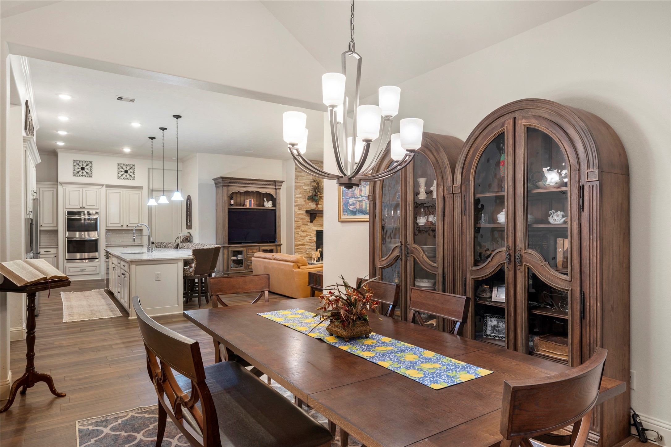Elegant open-concept dining and living area featuring a stylish chandelier, rich wood cabinetry, and a spacious kitchen island, perfect for entertaining and family gatherings.