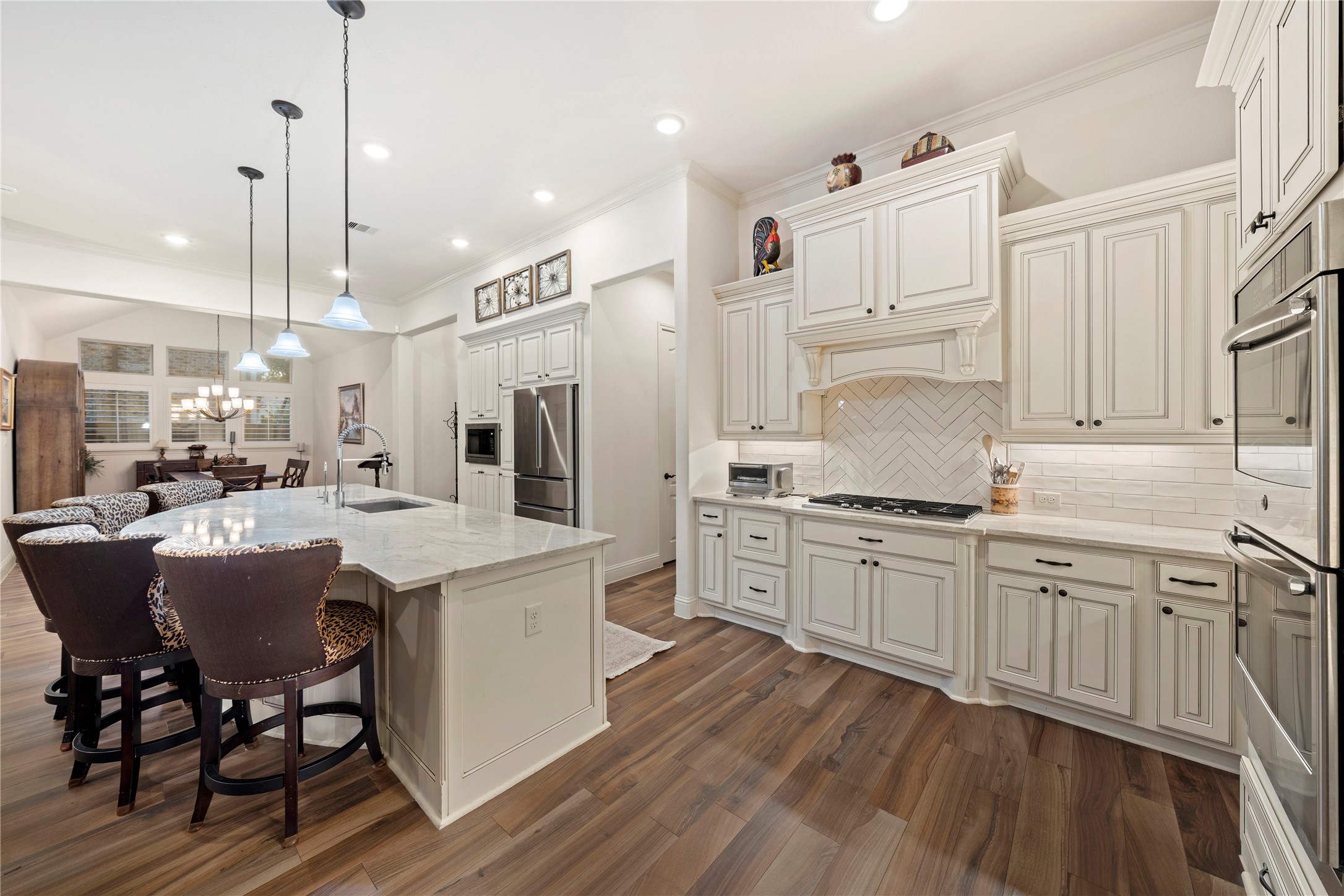 Elegant kitchen with custom white cabinetry, quartz countertops, and a spacious island. The open layout flows into a cozy dining area, perfect for entertaining.
