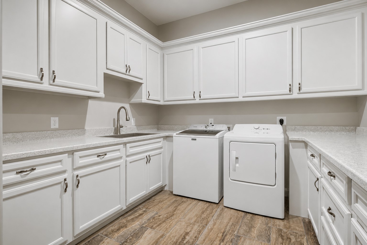 This well-designed laundry room offers exceptional functionality with a utility sink, ample storage, and plenty of workspace for all your household needs.