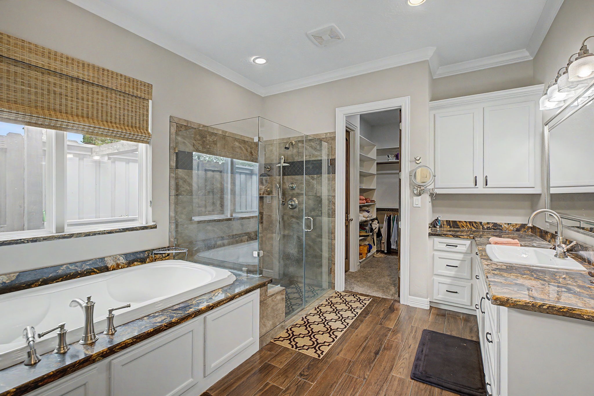 This spacious primary bathroom offers abundant storage and is conveniently connected to TWO large walk-in closets for added functionality and ease.