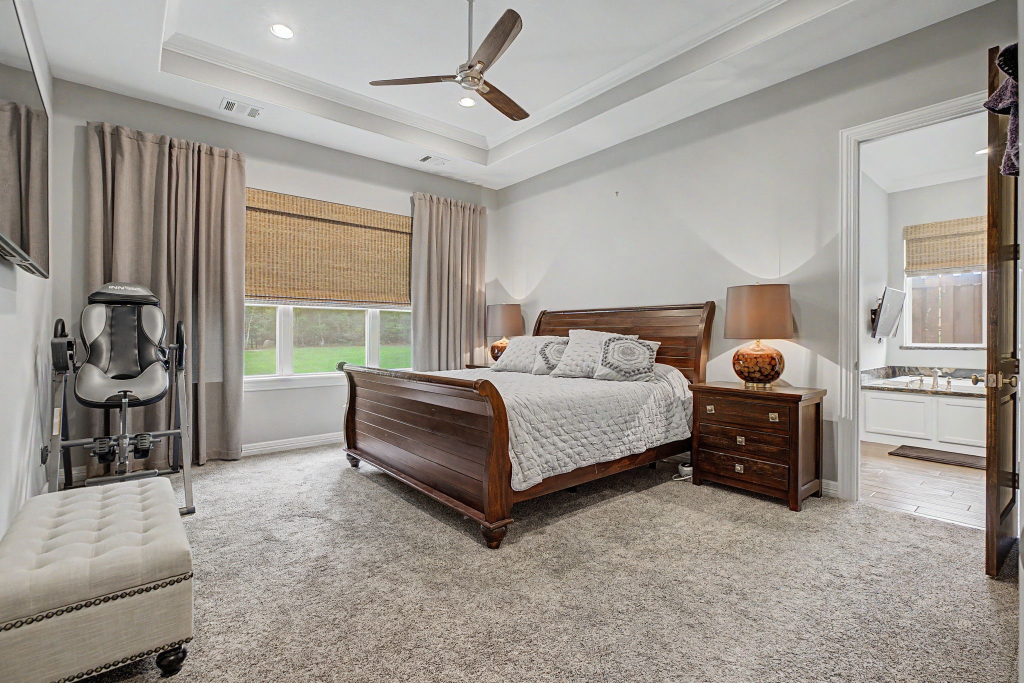 This spacious primary bedroom is filled with natural light and features elegant tray ceilings, creating a peaceful retreat with beautiful, serene views.
