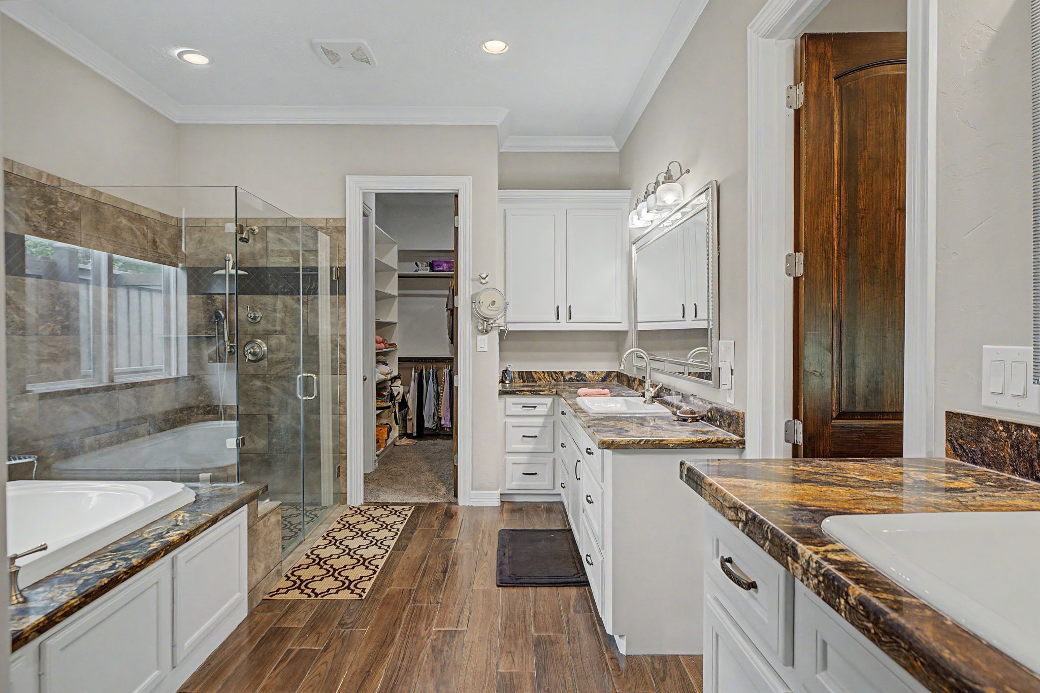 Indulge in this spa-like primary bathroom, complete with a spacious walk-in shower, soaking tub, dual vanities, and stylish finishes throughout.