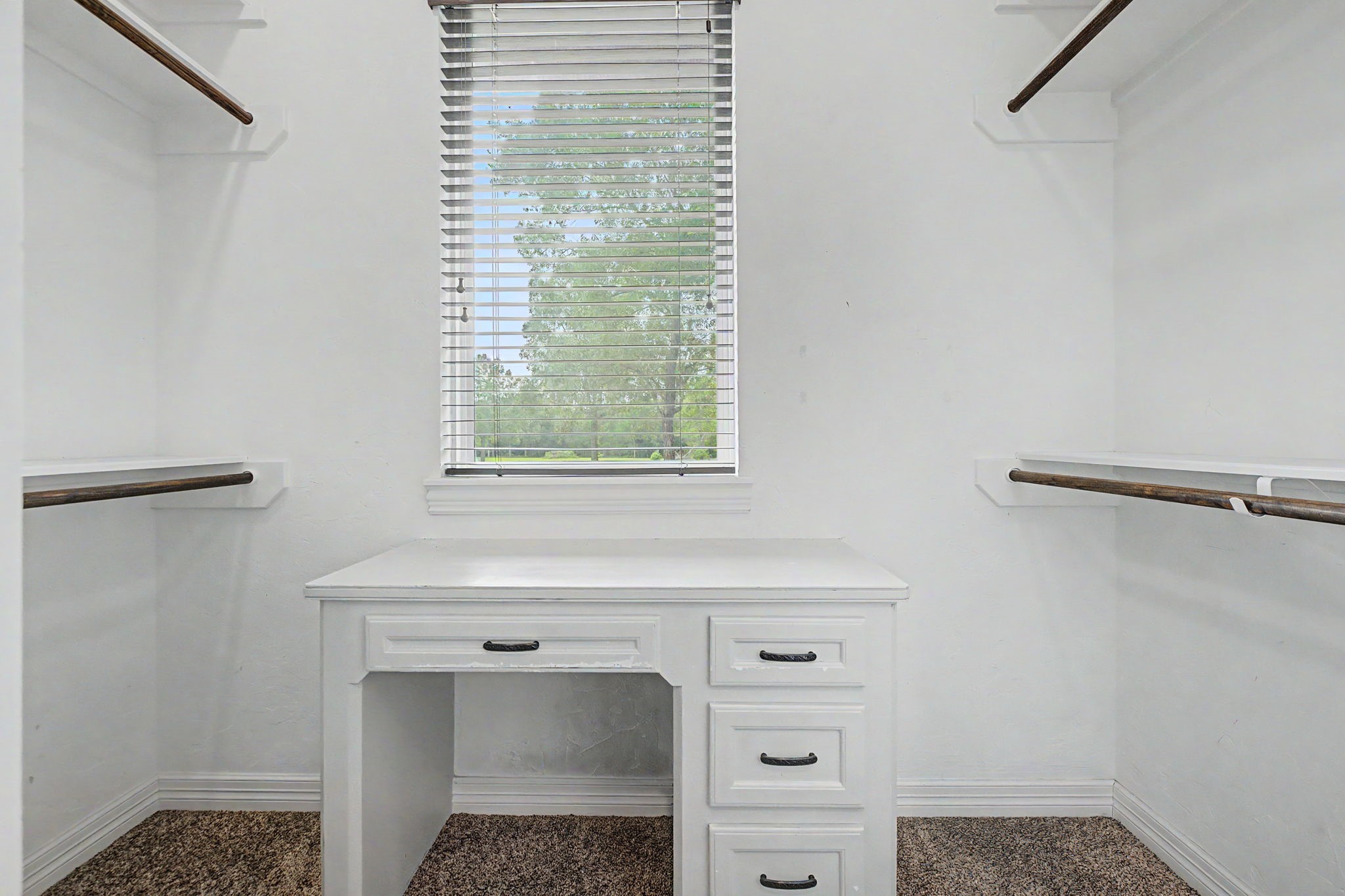 This spacious walk-in closet for Secondary Bedroom #1 features a built-in desk and a window that fills the space with natural light.