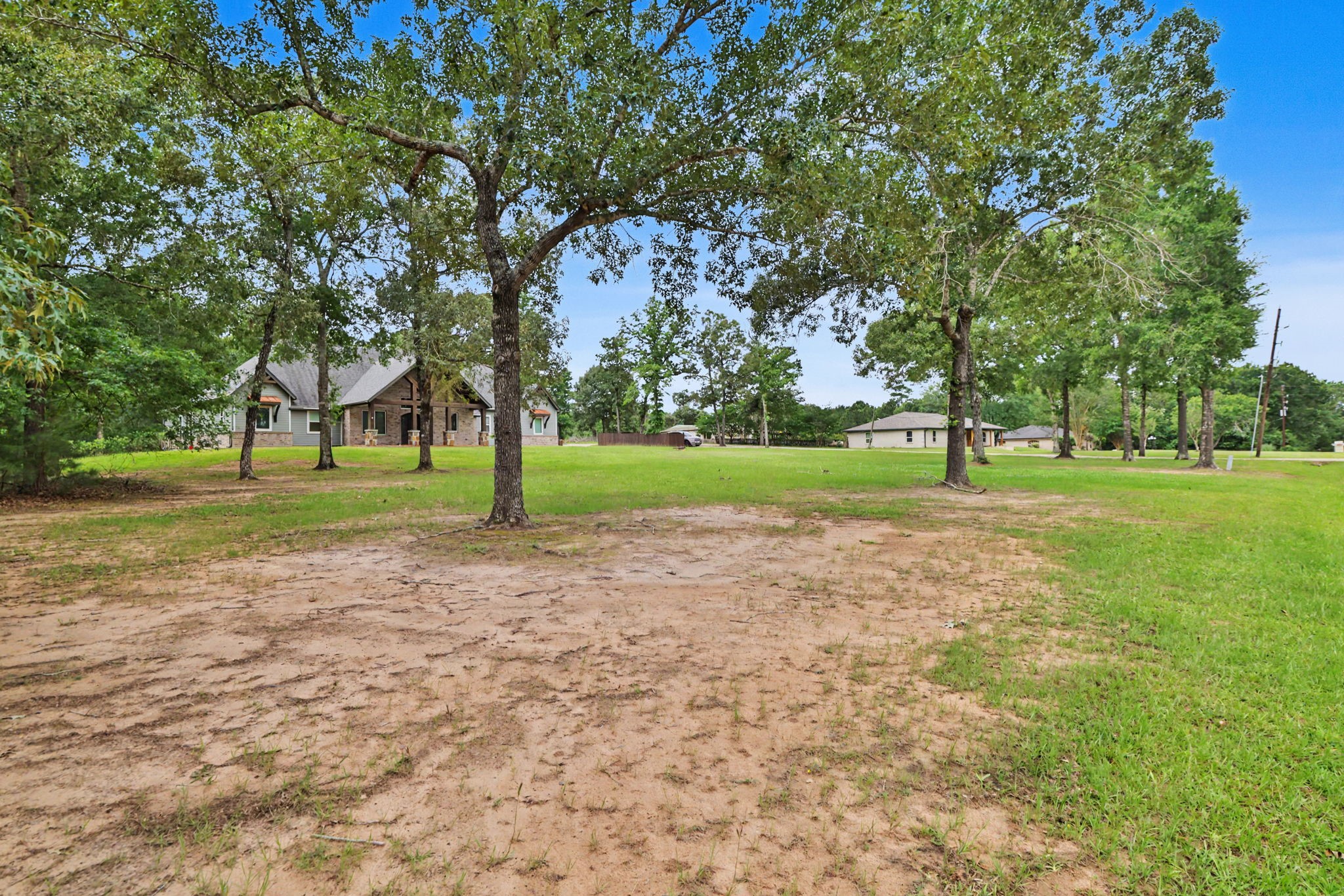 This view from the front corner highlights the property's generous outdoor space, beautiful setting, and custom home.