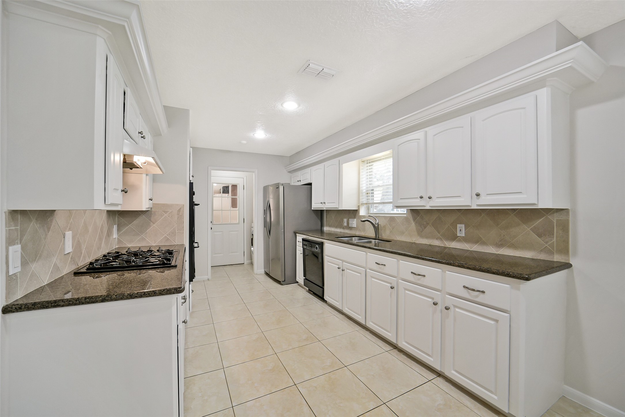 The kitchen features tile floors, granite counters with tile backsplash and recessed lighting.