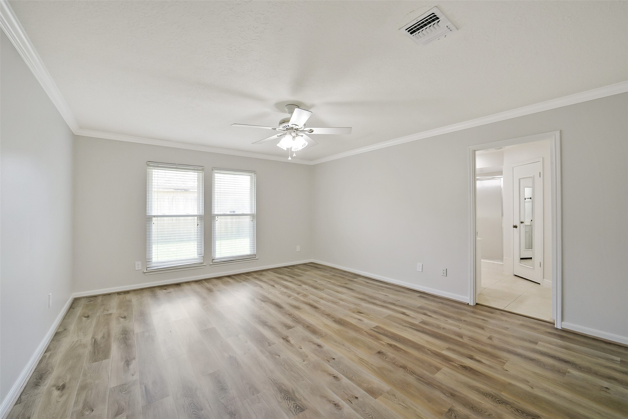 The primary bedroom features crown molding and a ceiling fan.