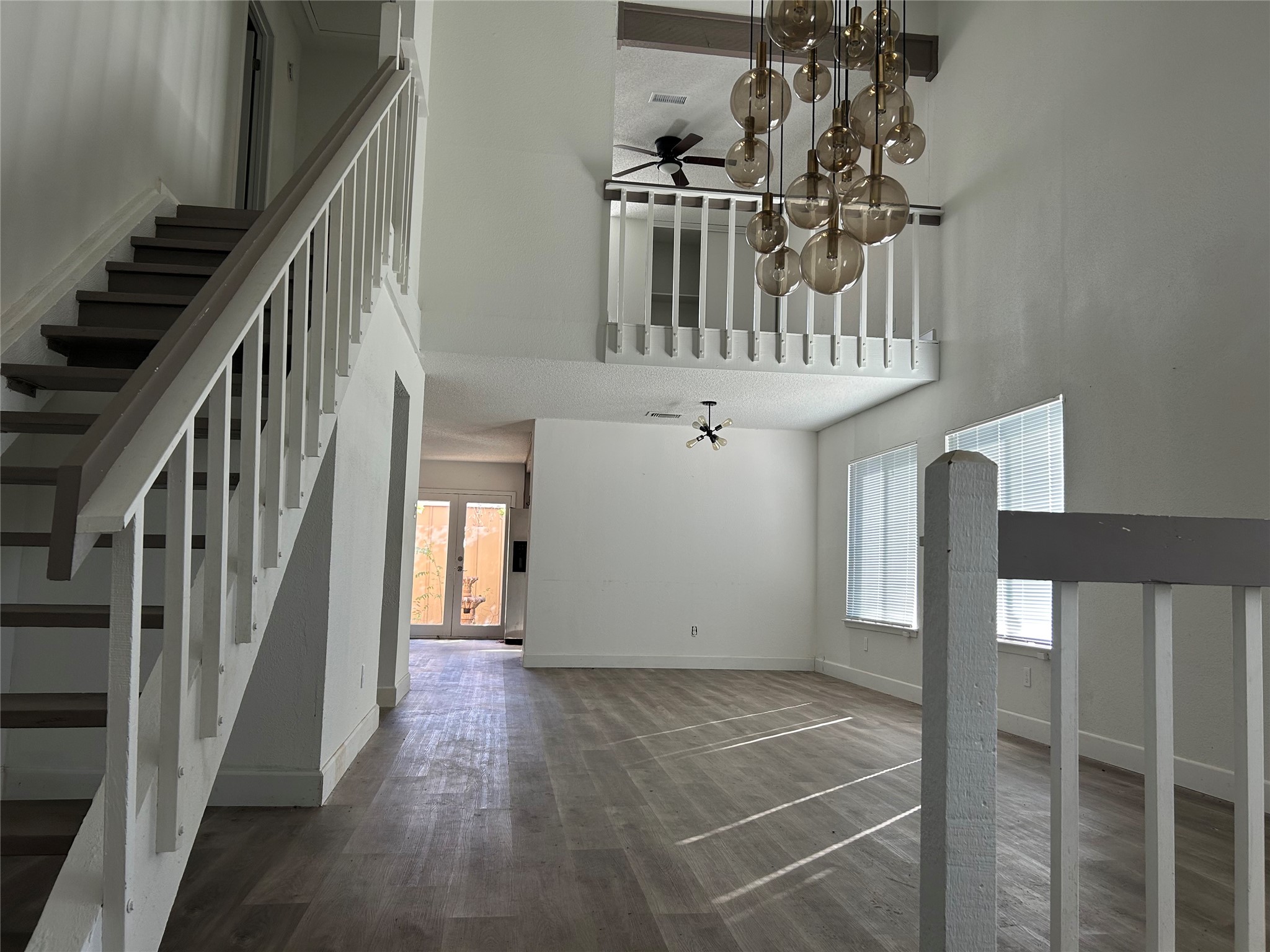 Expansive living room, dining area with high ceiling and large windows for natural light.
