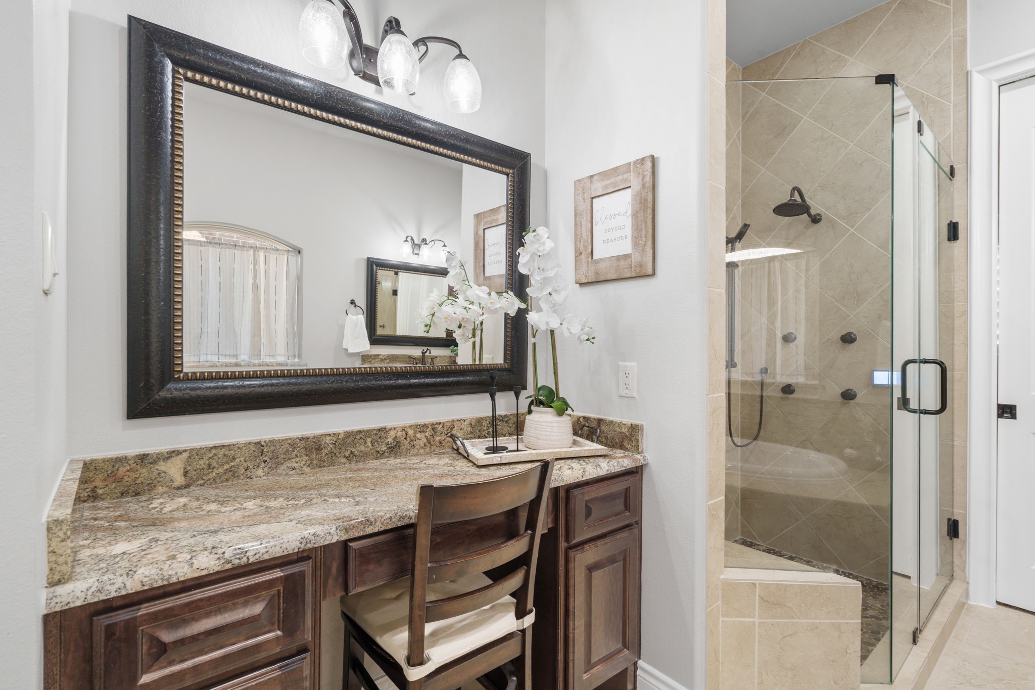 Dedicated makeup vanity with generous counter space alongside an oversized, glass-enclosed shower.