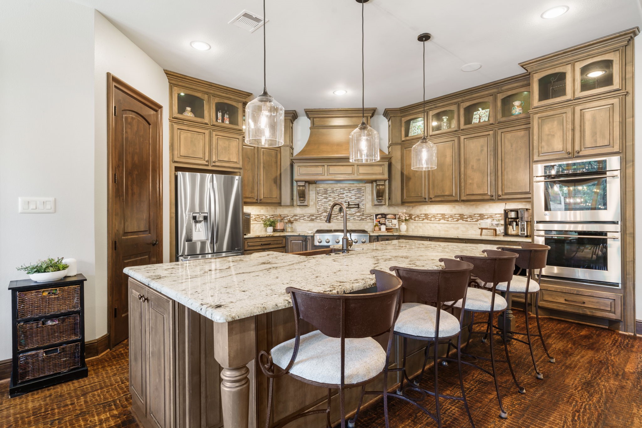 Stainless steel Monogram Appliances, double ovens, a professional-style 36' gas cook top, and decorative vent hood make this kitchen ideal for preparing food and entertaining.