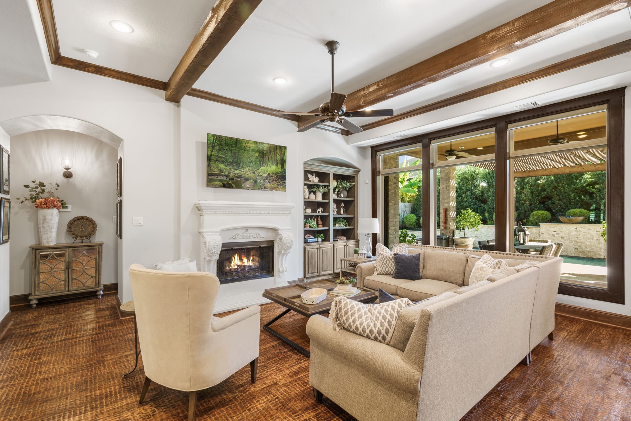 Oversized windows frame beautiful views of the backyard oasis, bringing natural light and outdoor scenery into the living space.