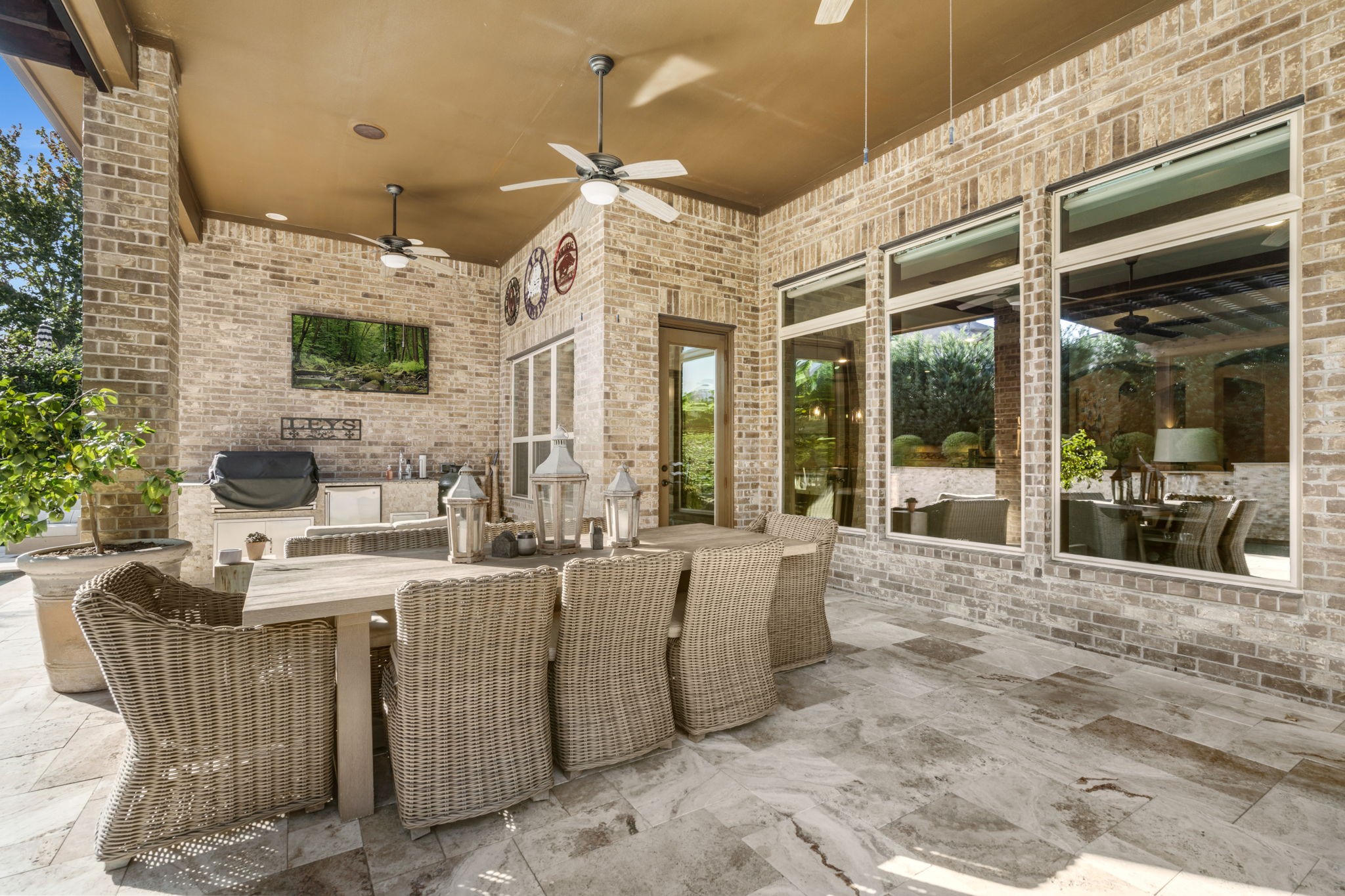 Expansive covered patio with beautiful stone flooring, ceiling fans, and plenty of room for outdoor dining and entertaining.