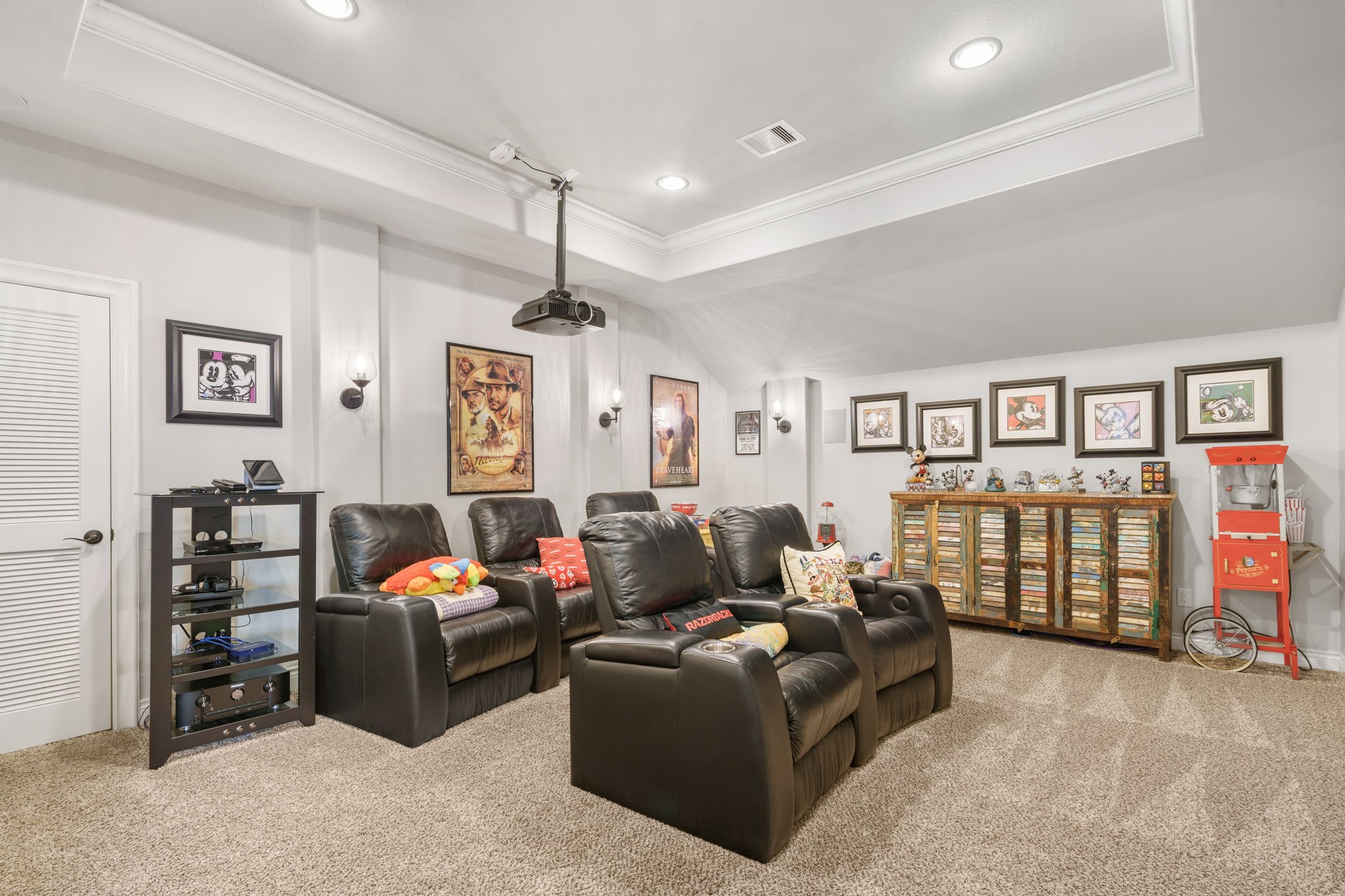 Dedicated media room features comfortable theater-style seating, recessed lighting, and a ceiling-mounted projector for movie nights at home.