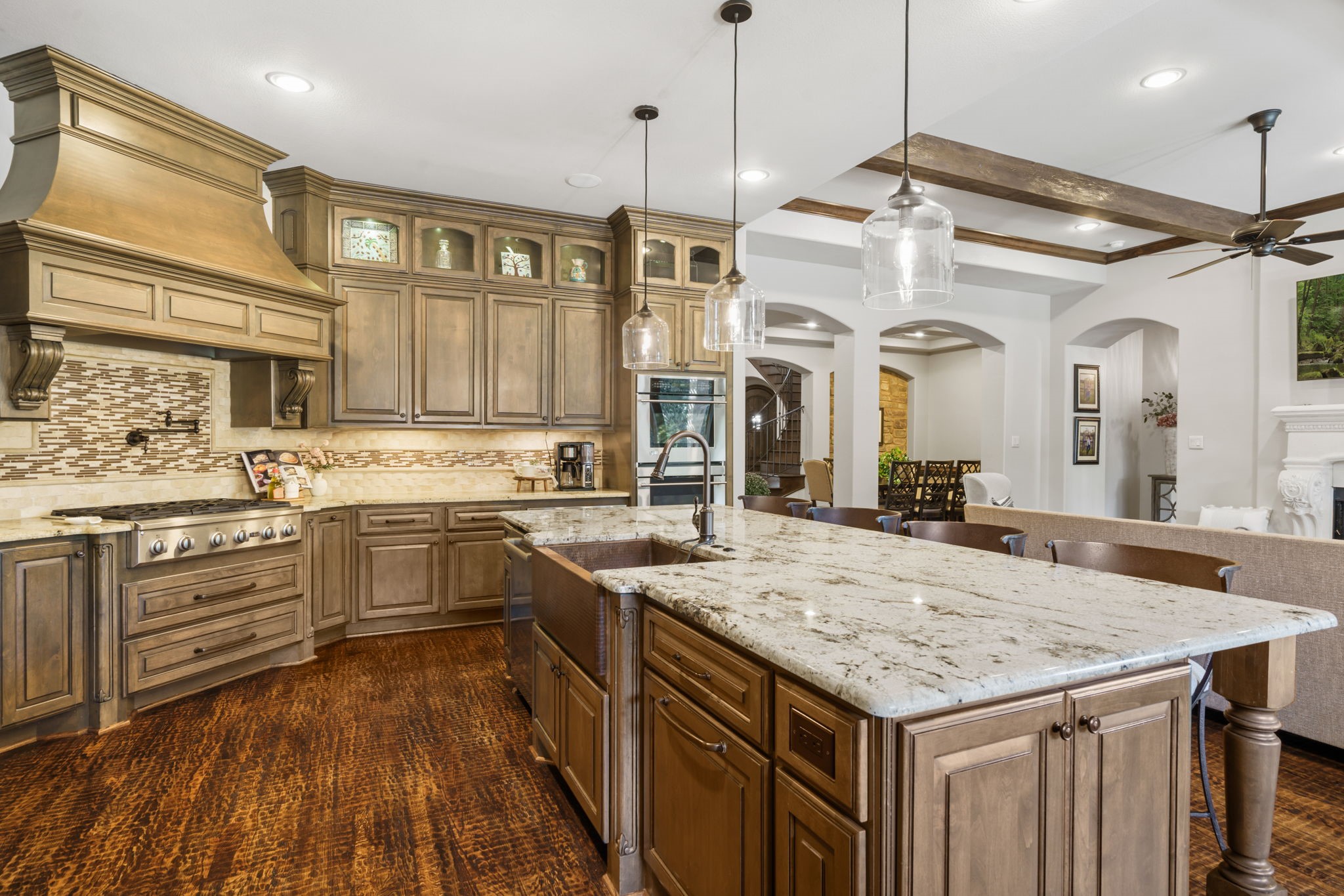 Rich cabinetry with glass-front display accents, under-cabinet lighting, and a decorative tile backsplash add warmth and character.