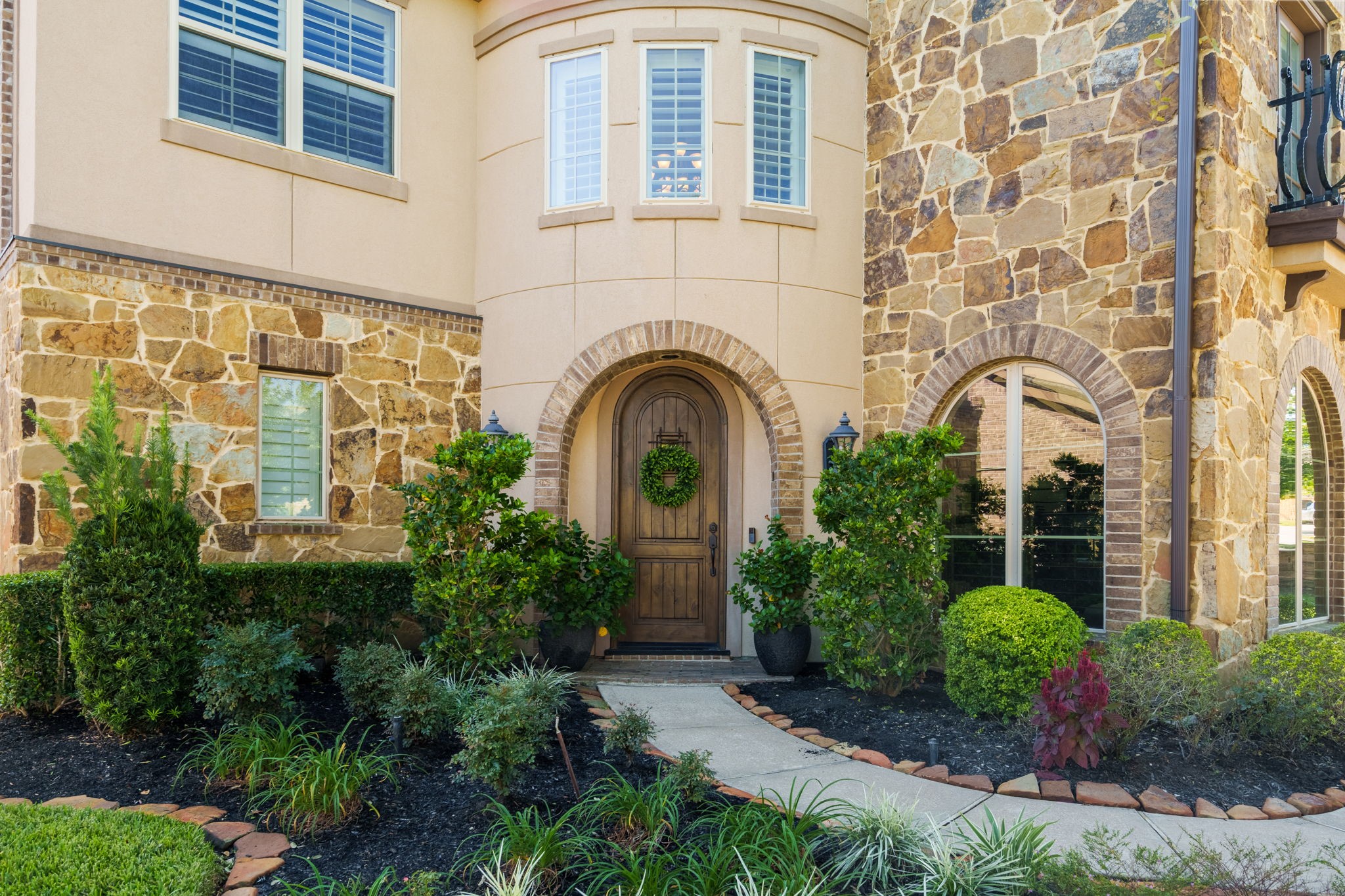 An inviting arched wood front door framed by brick detailing welcomes you into this beautiful home.