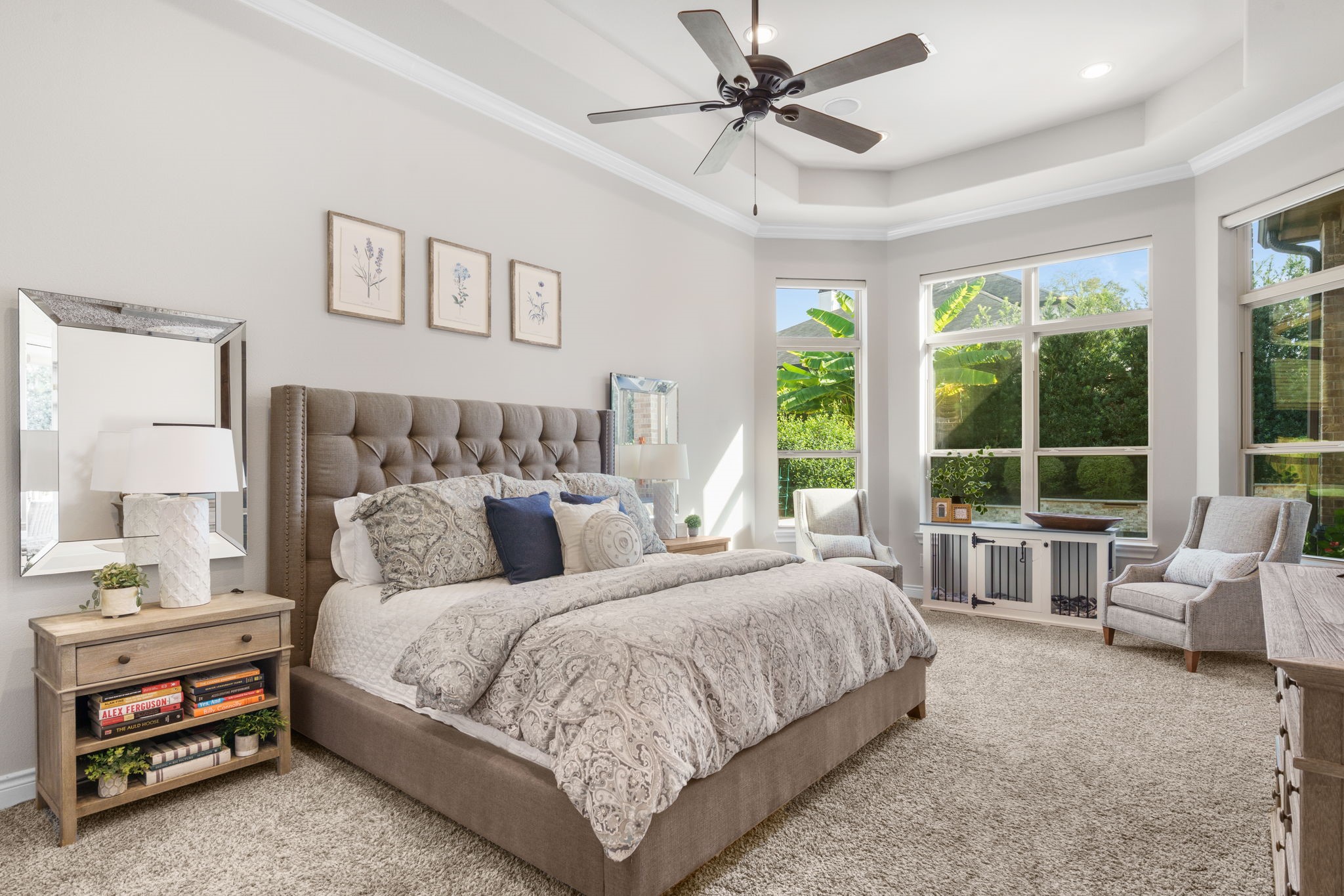 Spacious primary retreat featuring a tray ceiling, crown molding, and a beautiful wall of windows overlooking the backyard.