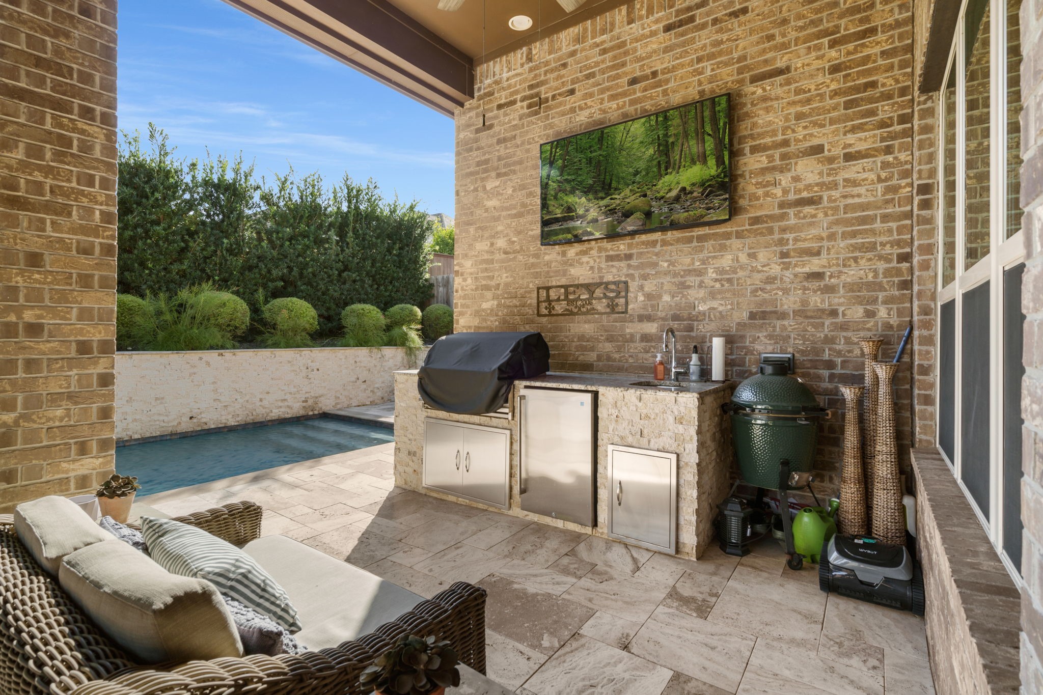 Outdoor kitchen features a built-in grill, sink, refrigerator, and stone countertops for year-round entertaining.