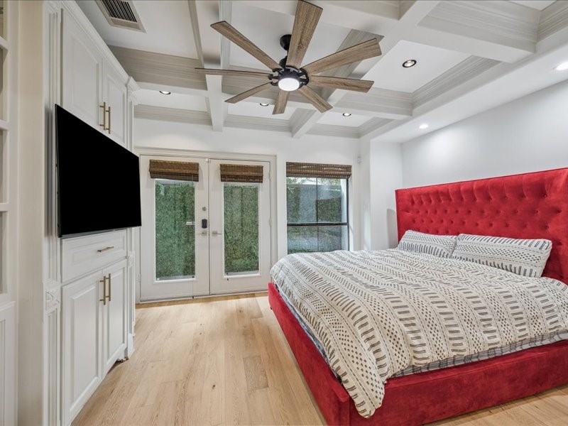 Unwind in a bedroom full of character, featuring detailed ceiling woodwork, built-in shelving, generous storage, and a ceiling fan for added comfort. A privacy fence and spacious backyard behind the room complete this inviting retreat.