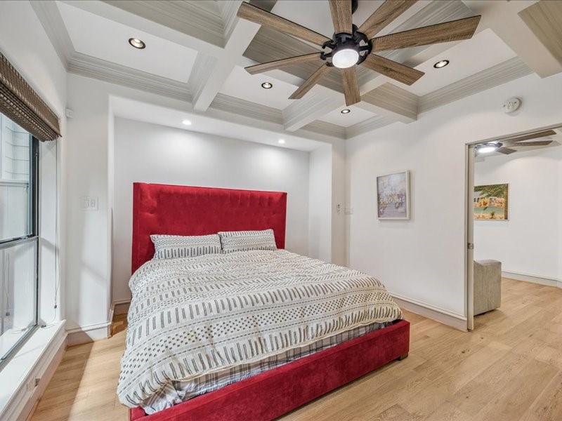 Unwind in a bedroom full of character, featuring detailed ceiling woodwork, built-in shelving, generous storage, and a ceiling fan for added comfort. A privacy fence and spacious backyard behind the room complete this inviting retreat.