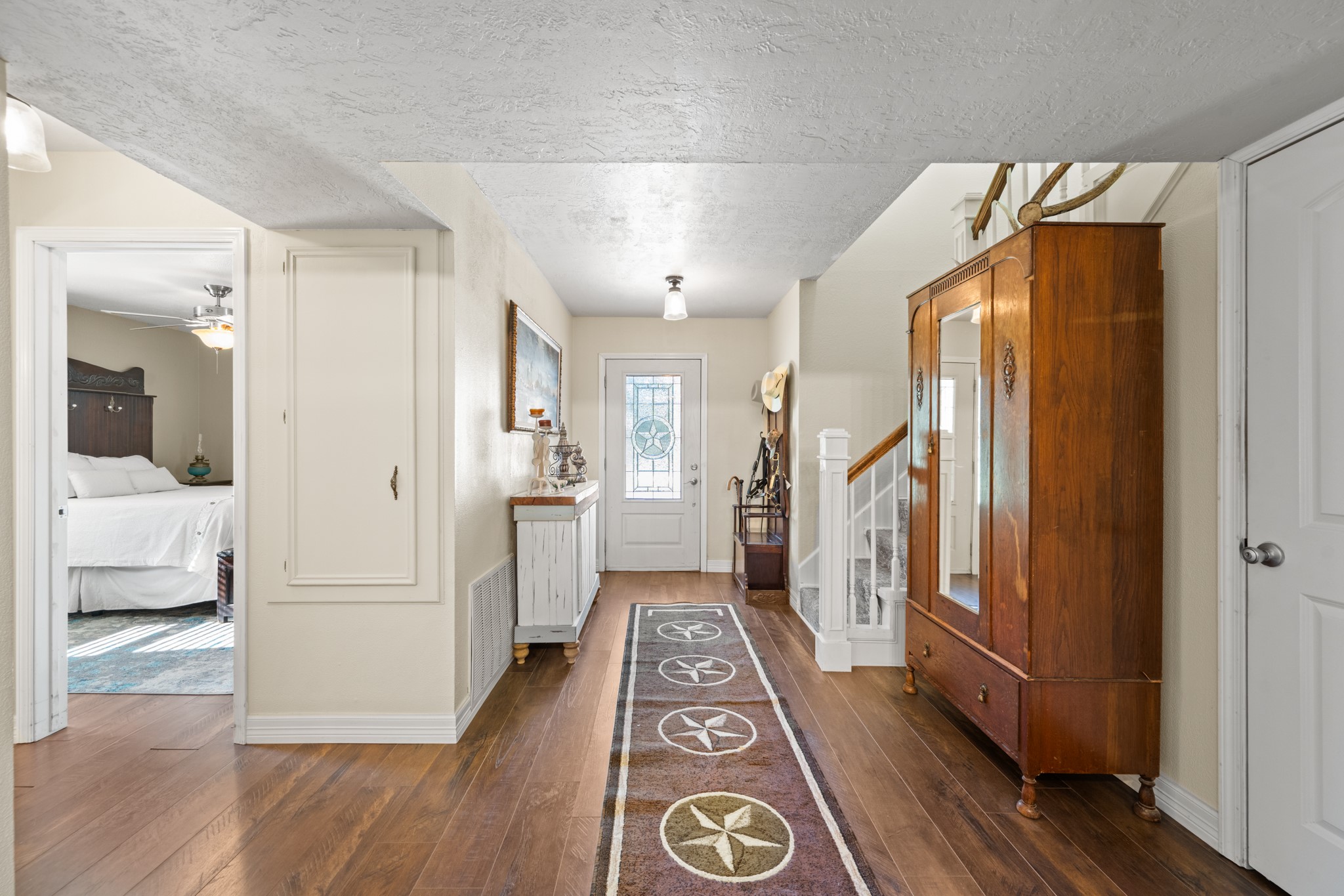 Welcoming entryway showcases warm wood-look flooring, a decorative glass front door with a Texas star design, and a staircase with white balusters and wood handrail. Welcoming entryway showcases warm wood-look flooring, a decorative glass front door with a Texas star design, and a staircase with white balusters and wood handrail.