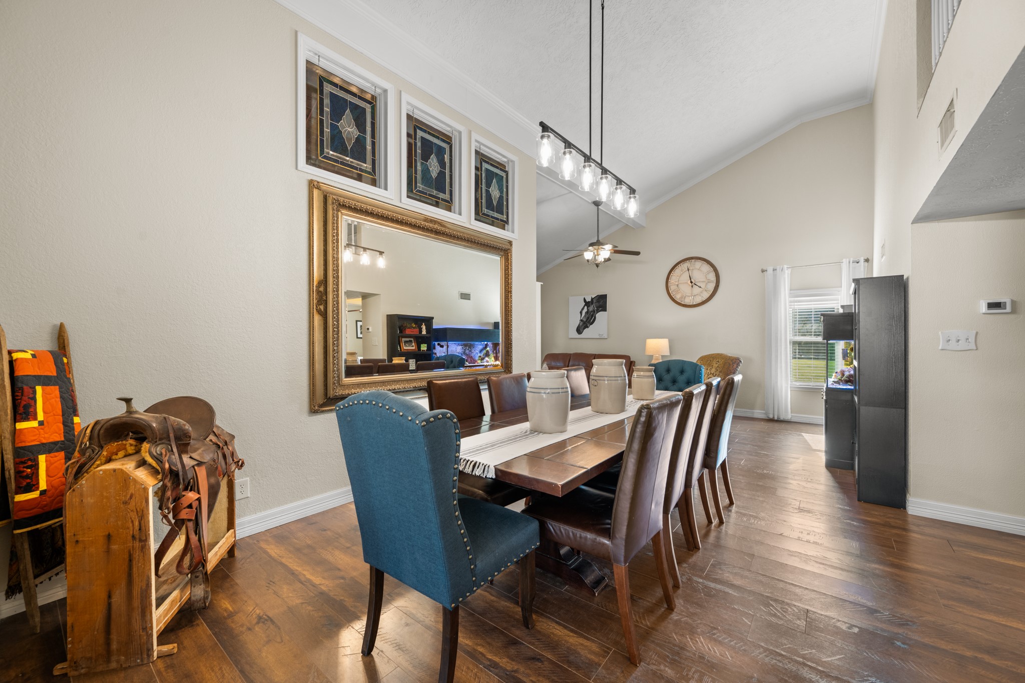Spacious formal dining area features soaring ceilings, decorative stained-glass accent windows, elegant pendant lighting, and warm wood-look flooring, offering plenty of room for gatherings and entertaining. Spacious formal dining area features soaring ceilings, decorative stained-glass accent windows, elegant pendant lighting, and warm wood-look flooring, offering plenty of room for gatherings and entertaining.