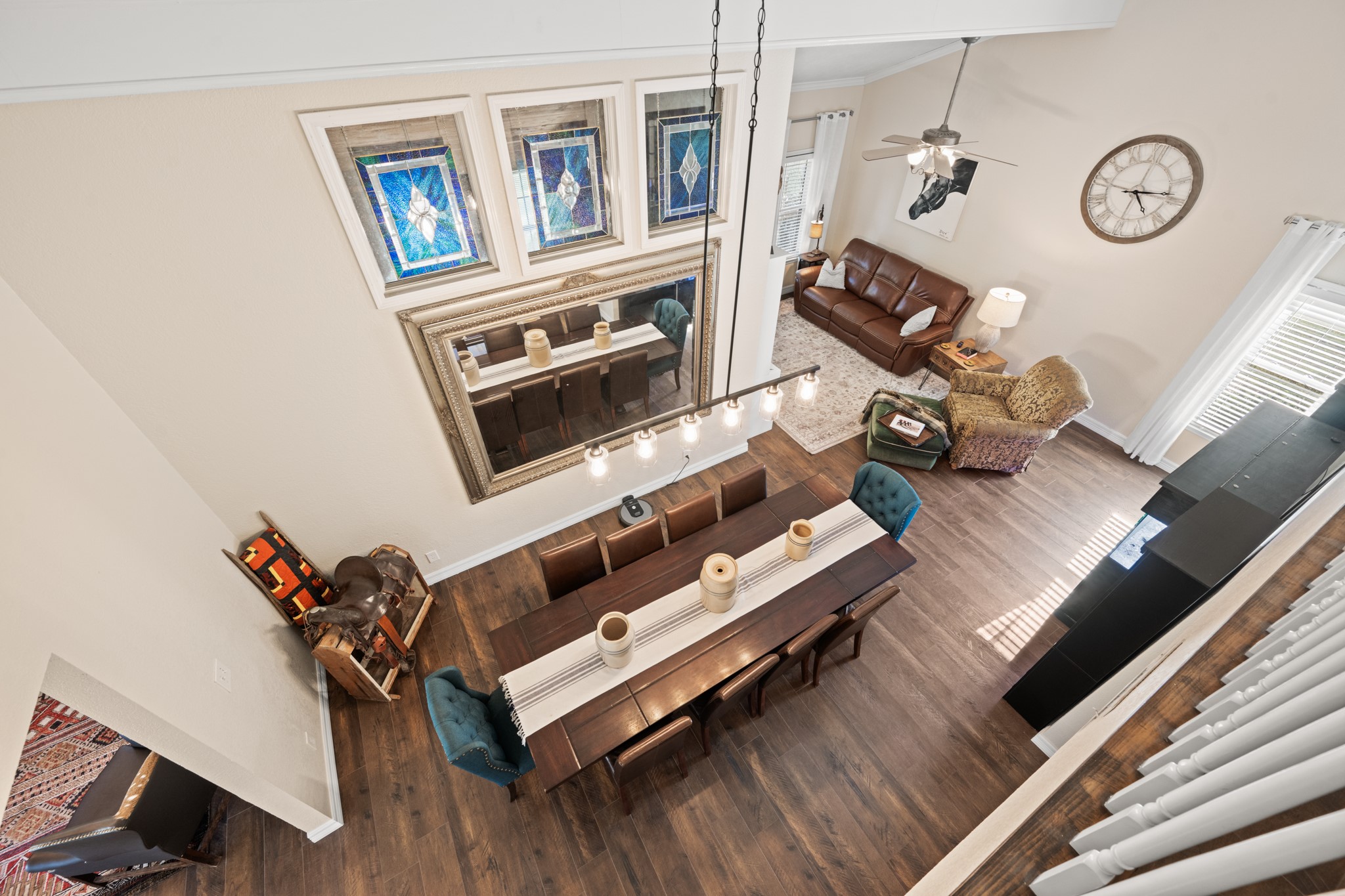 An impressive view from above showcases the home's soaring ceilings, open dining and family room layout, decorative stained-glass windows, and warm wood-look flooring.