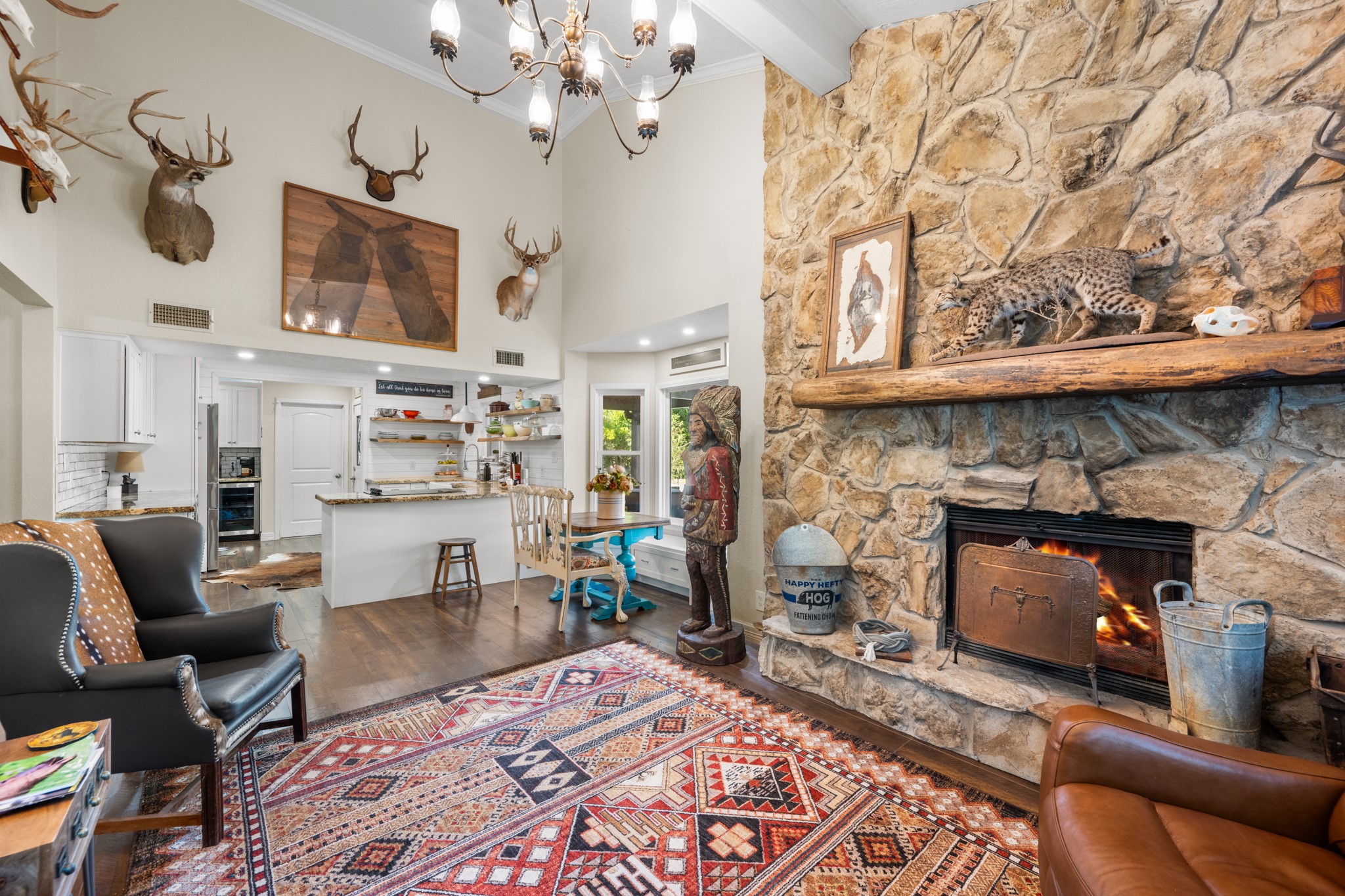 An impressive stone fireplace and vaulted ceilings create a striking focal point, while the open layout connects the living room to the farmhouse-style kitchen and breakfast nook.