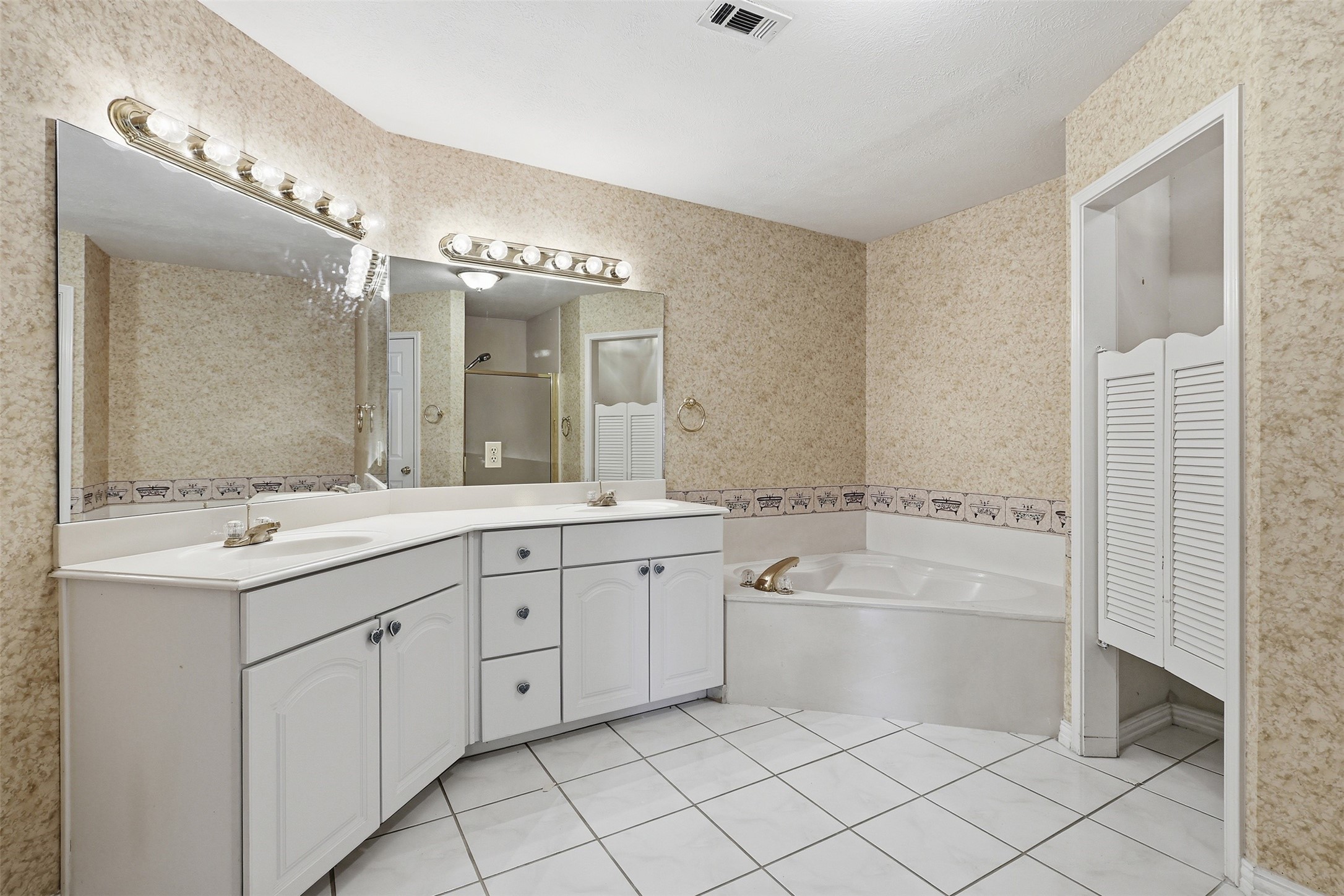 well-appointed en-suite bath featuring dual vanities, soaking tub, and separate shower
