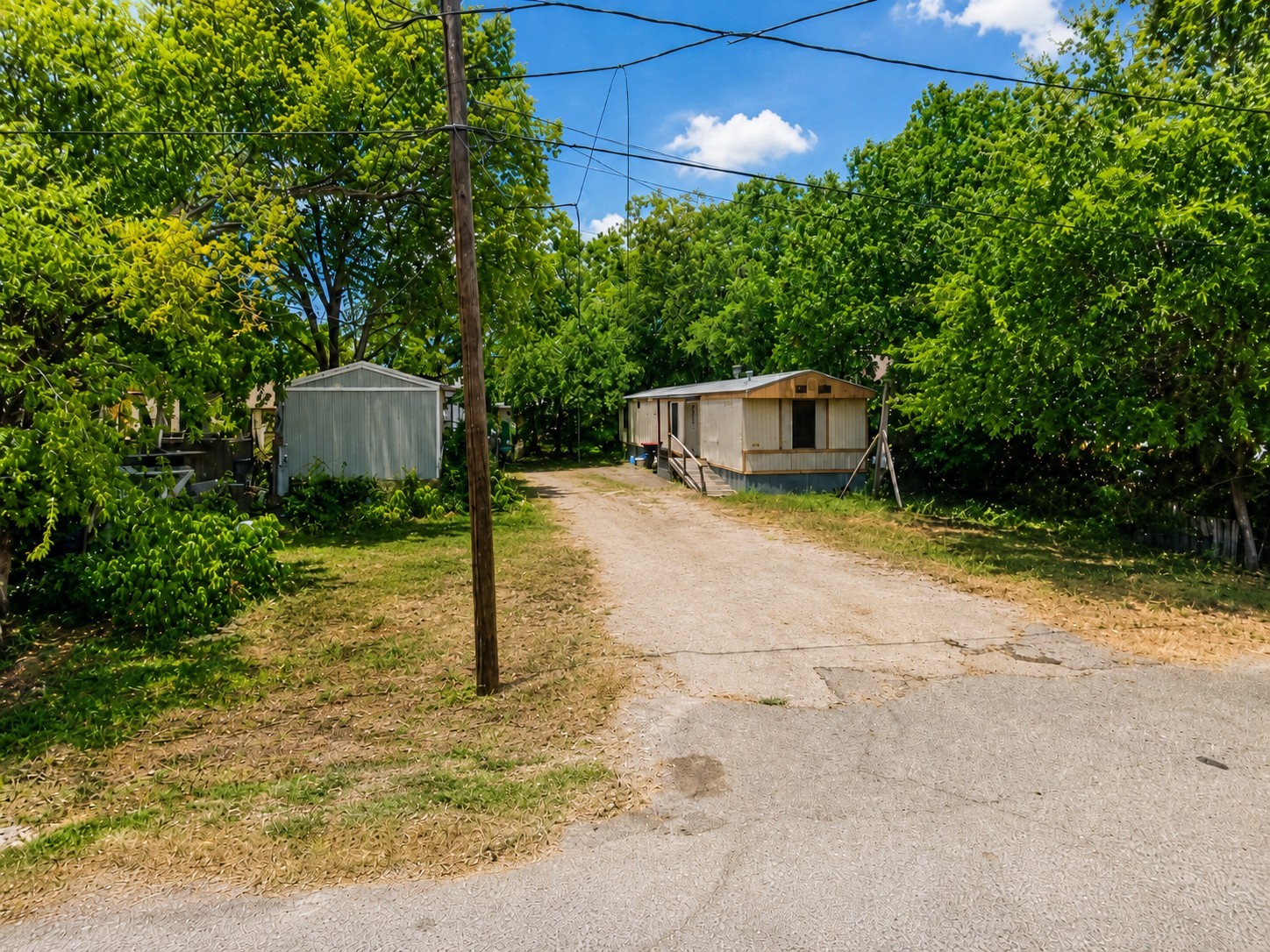 Spacious front entry with an extended driveway and a generous lot offering ample parking and outdoor space, creating a private setting with convenient street access. Property includes two mobile homes currently used as rental units with tenants in place, offering income-producing potential.