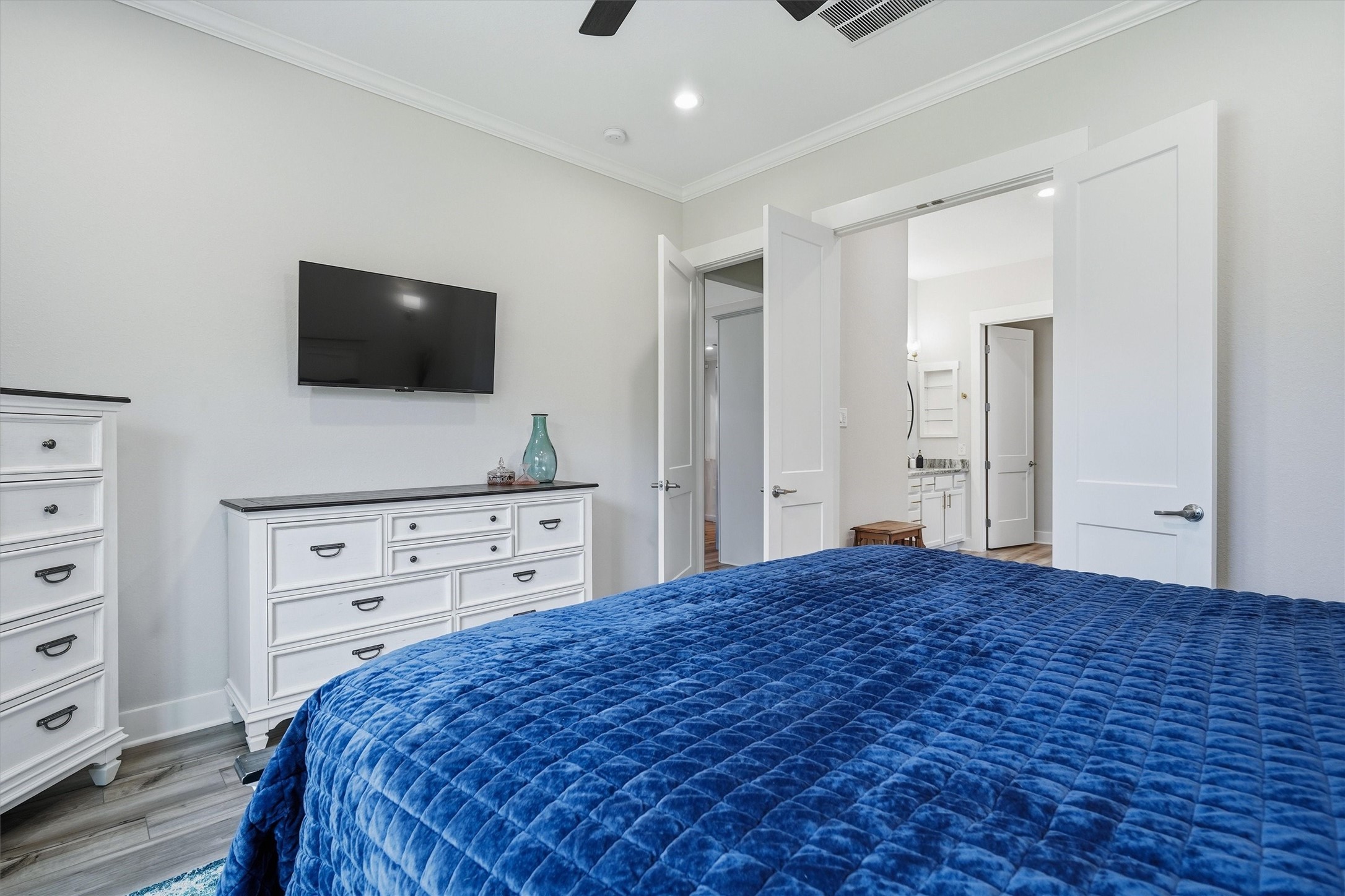 Primary bedroom with ceiling fan, en suite bath and crown molding