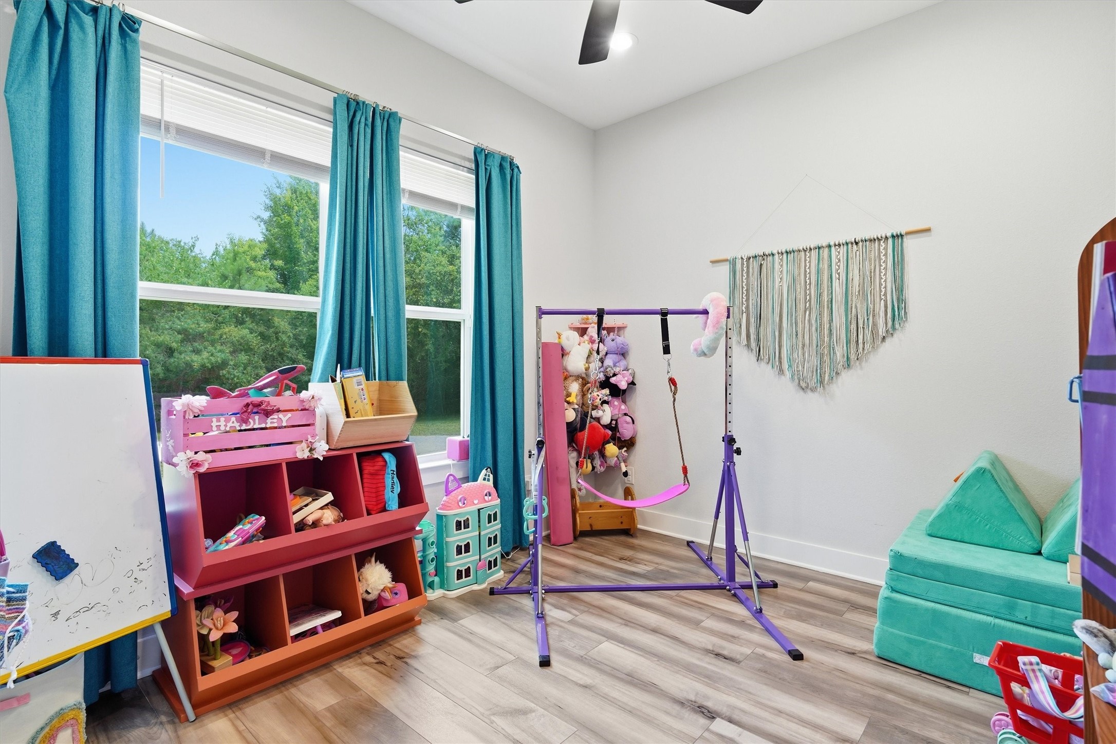 Secondary bedroom with high ceiling, ceiling fan and windows overlooking front yard