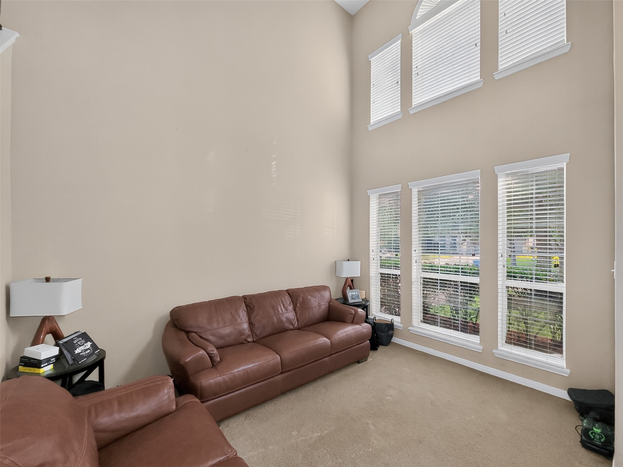 Spacious living area with soaring ceilings, abundant natural light from large windows, and comfortable leather seating, perfect for relaxation and entertaining.
