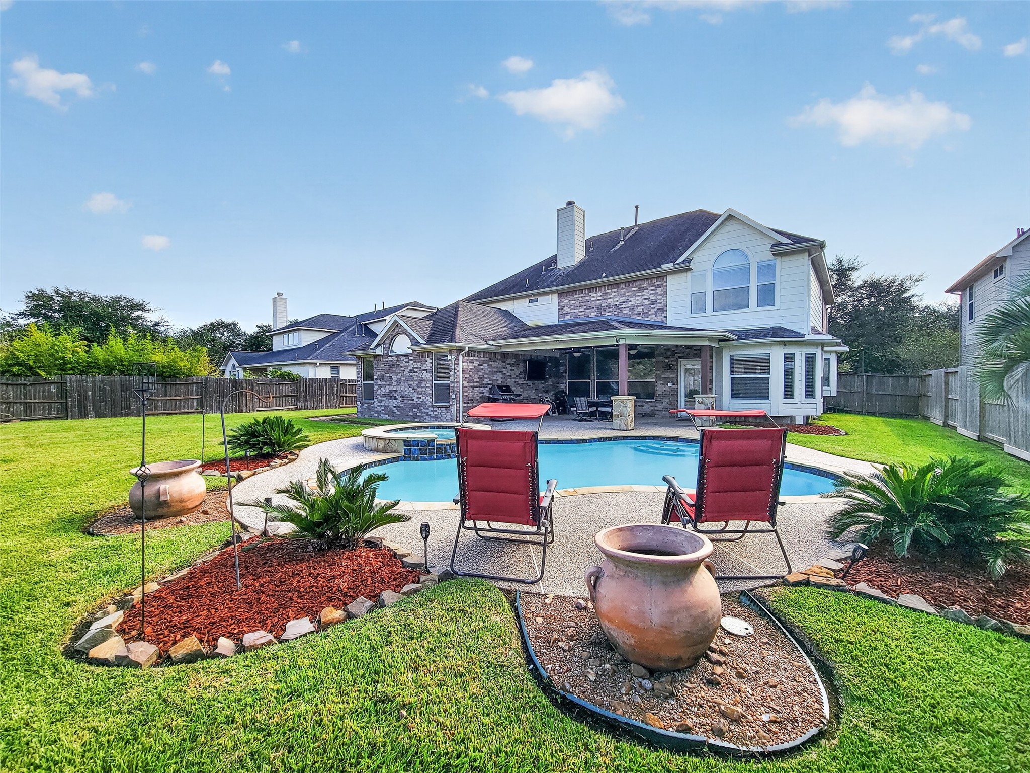 Enjoy outdoor living in this spacious backyard featuring a sparkling pool, lush landscaping, and a charming covered patio perfect for entertaining.