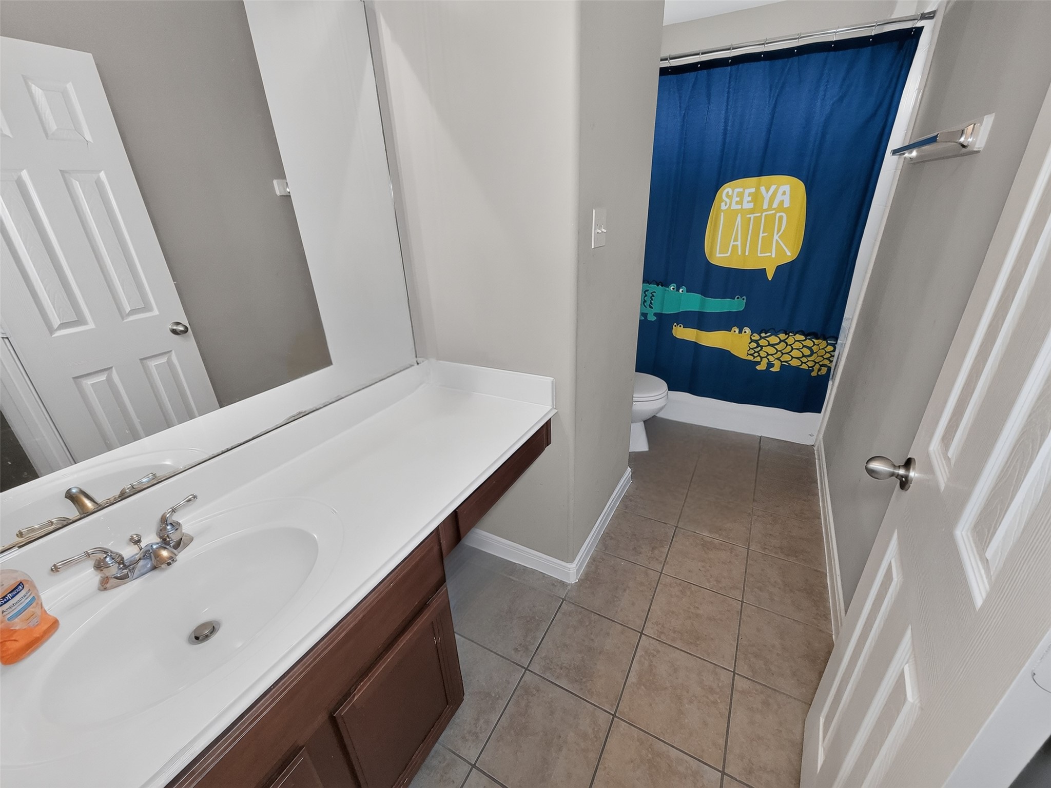 Charming bathroom featuring a large vanity, modern fixtures, and playful shower curtain, offering a cozy and functional space.
