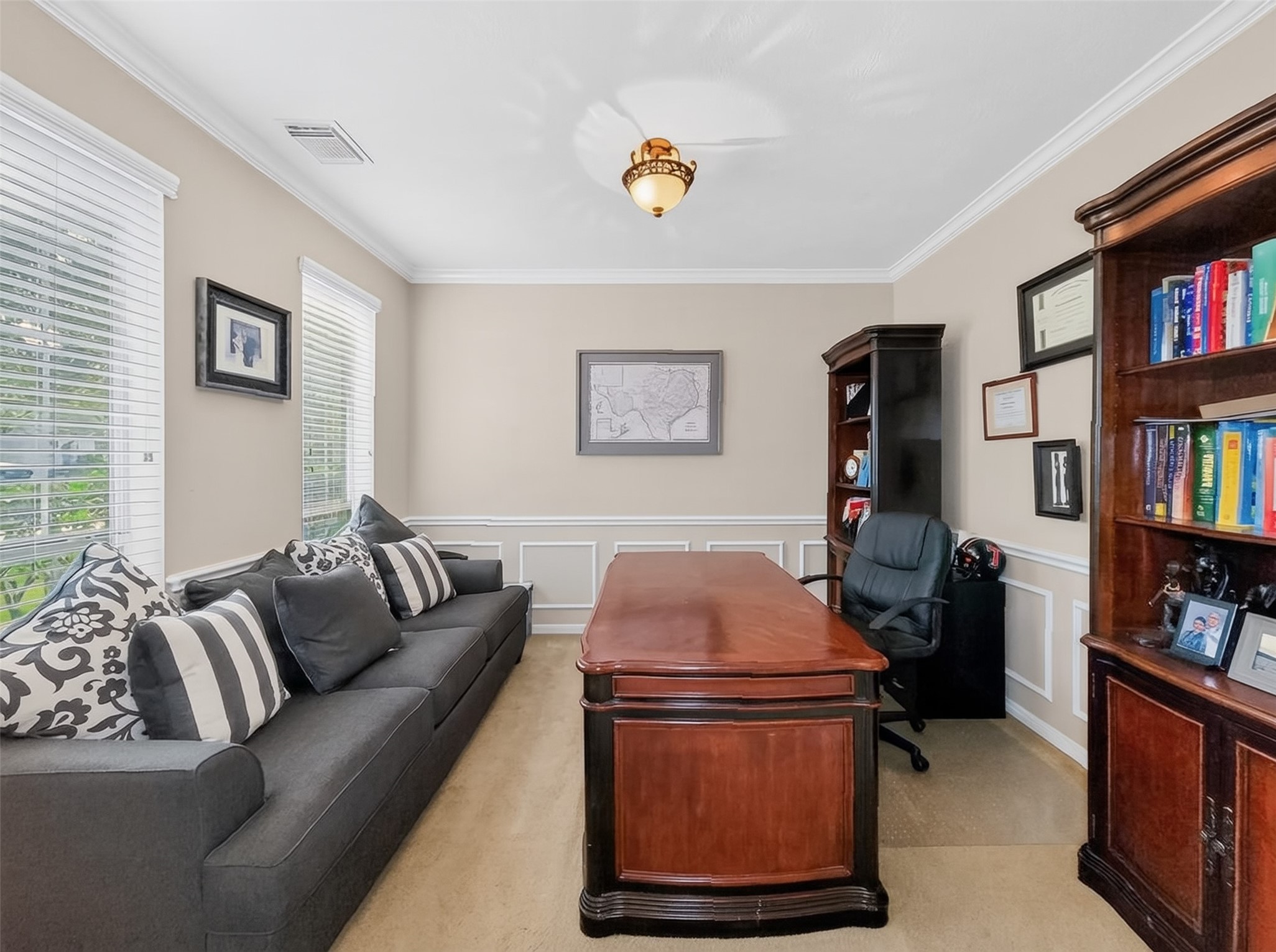 Elegant home office with rich wood furnishings, built-in bookshelves, and ample natural light from large windows, creating a sophisticated and inviting workspace.
