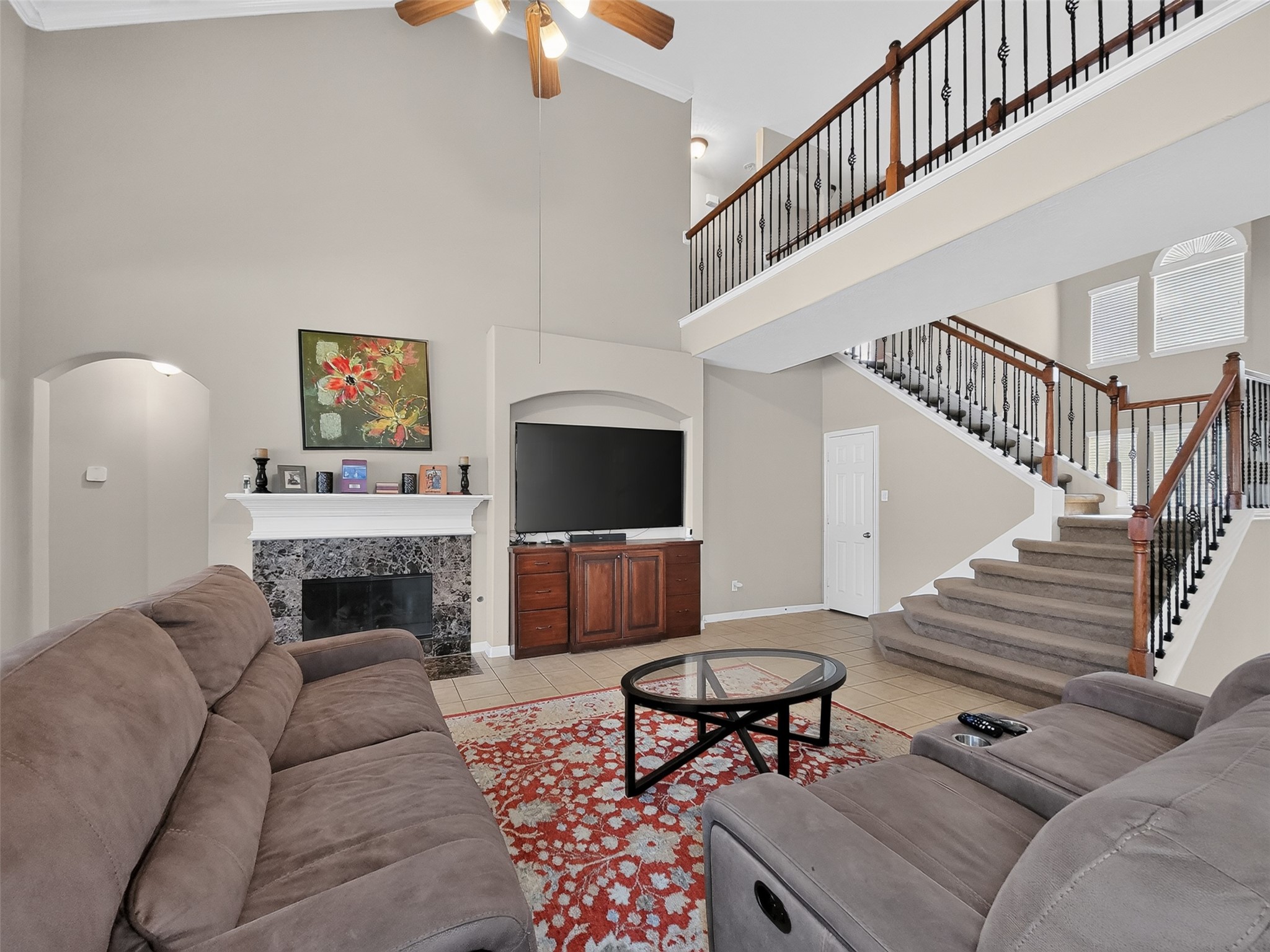 Spacious living area featuring a cozy fireplace, vaulted ceilings, and an elegant staircase, perfect for relaxation and entertaining.