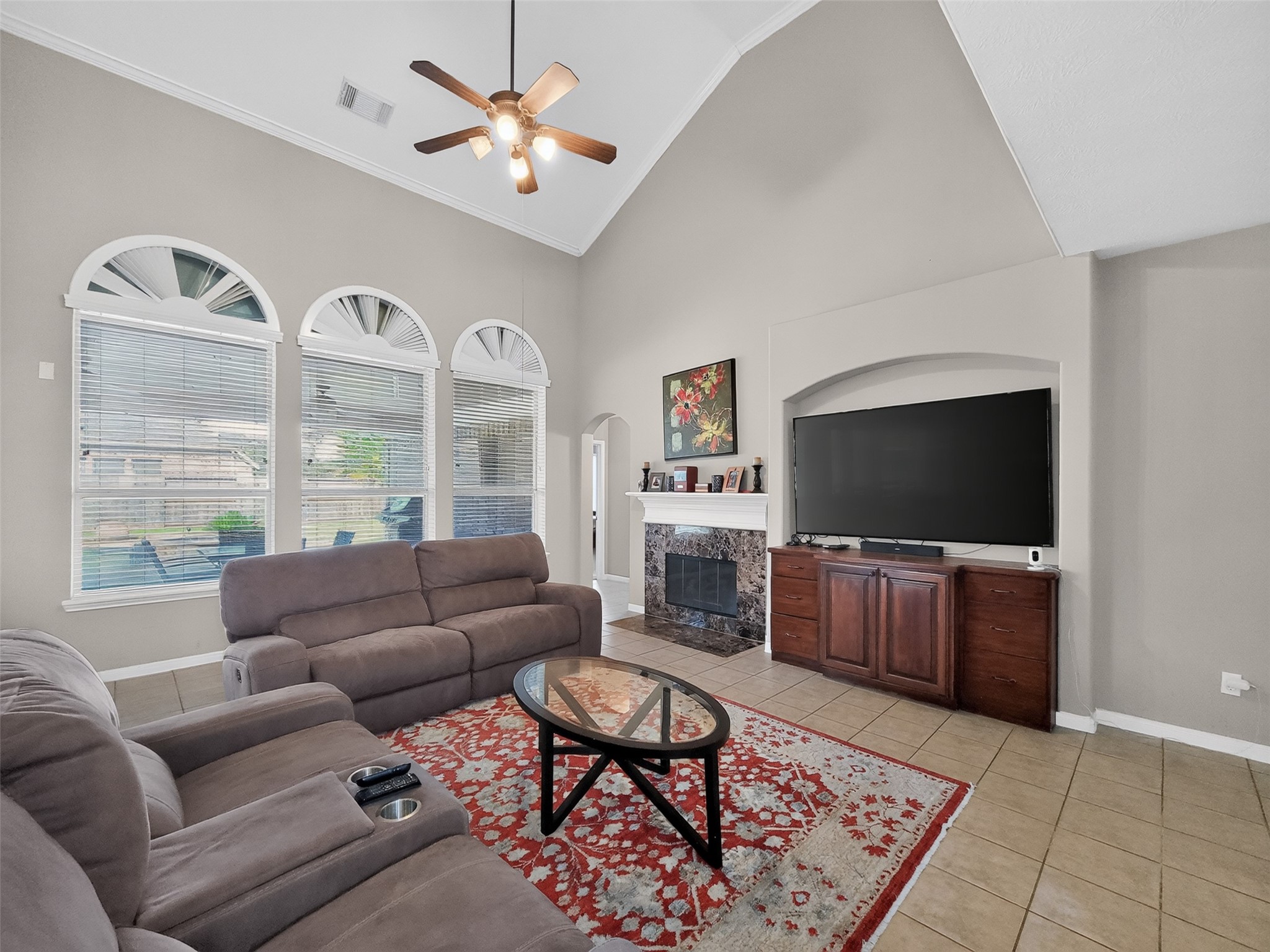 Spacious living room with high ceilings, abundant natural light from arched windows, and a cozy fireplace.