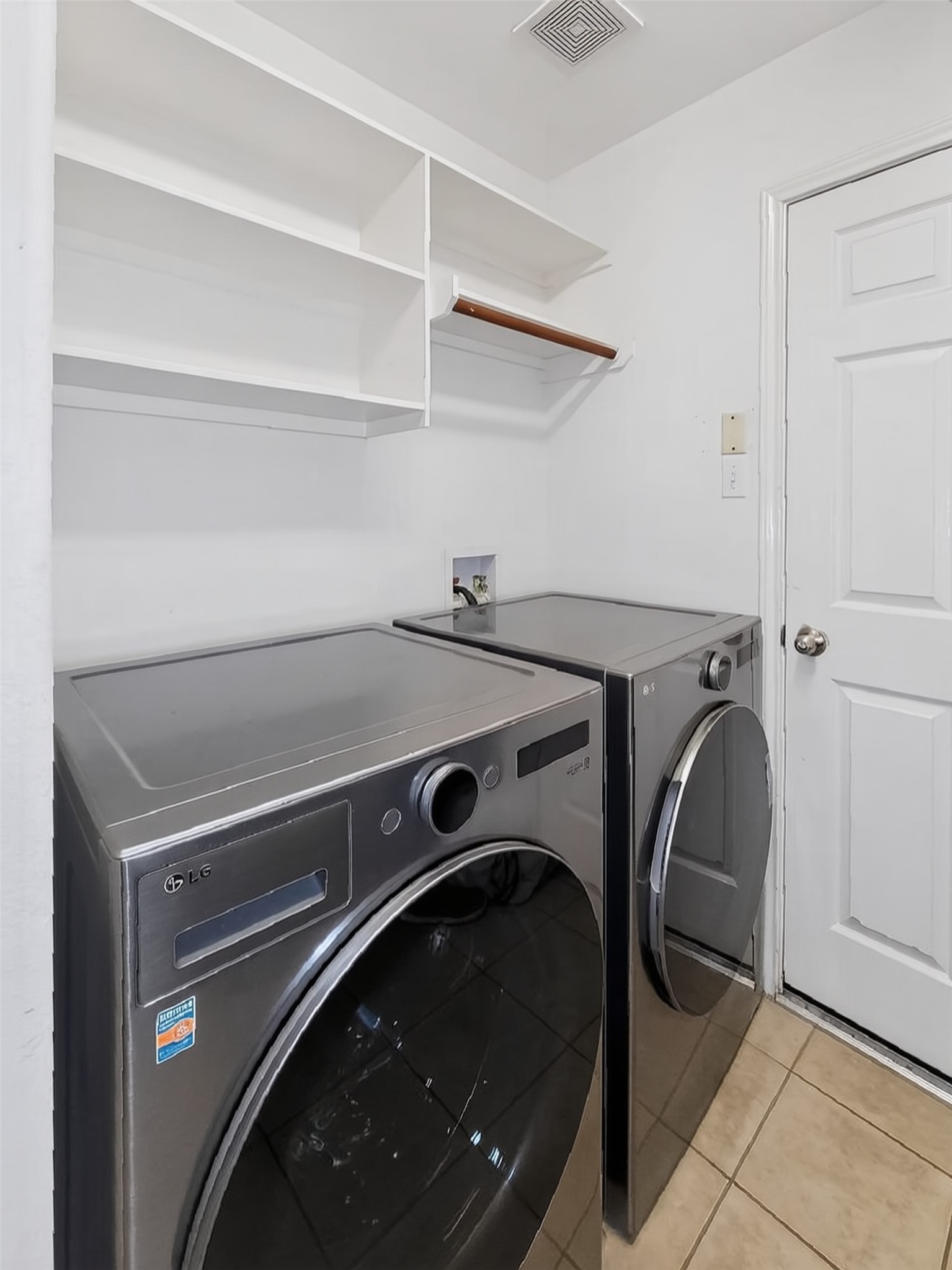 Efficient laundry room featuring modern washer and dryer, ample shelving, and convenient storage solutions.