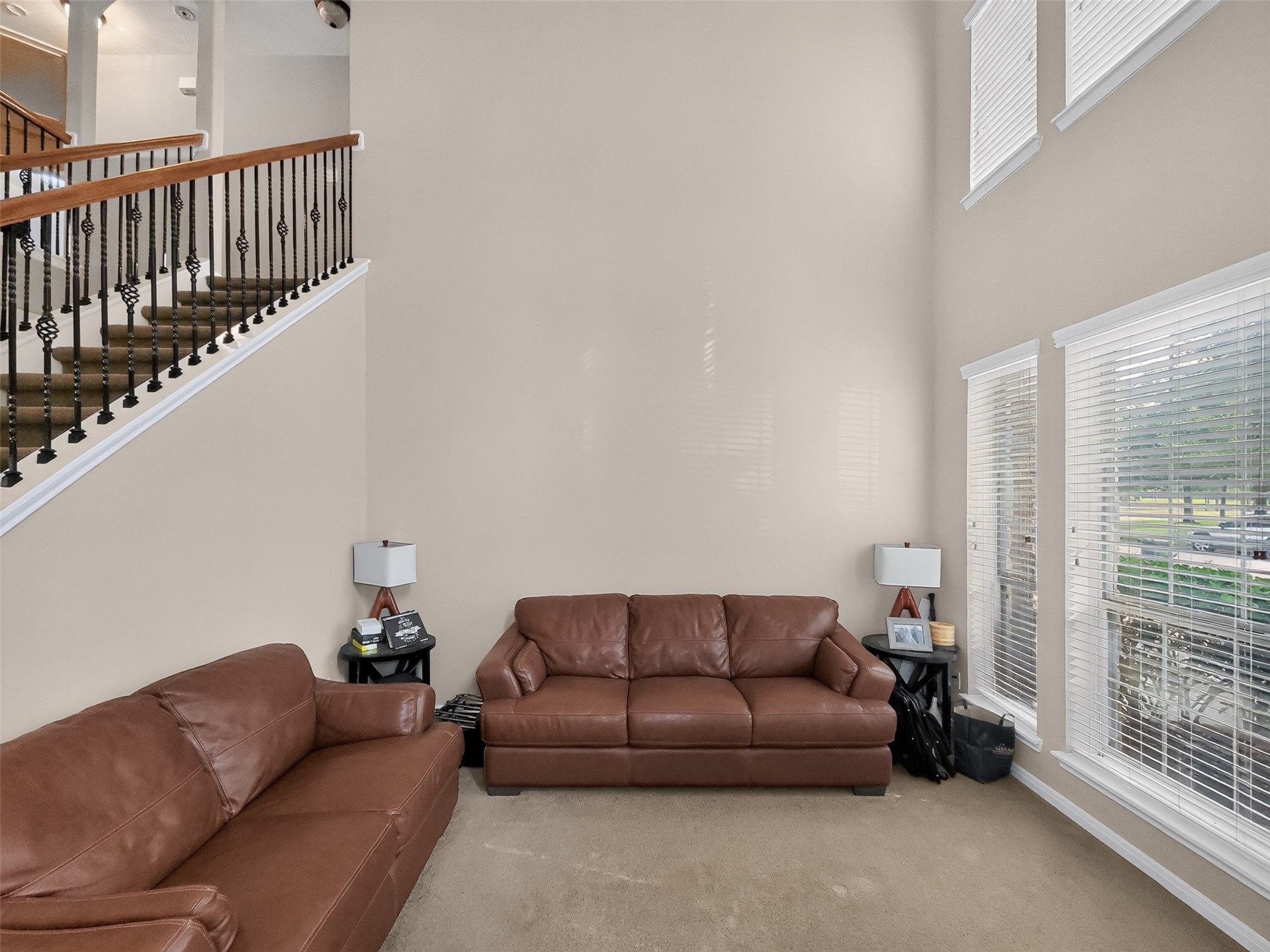 Spacious living area with high ceilings, natural light from large windows, and elegant staircase, creating a welcoming atmosphere.